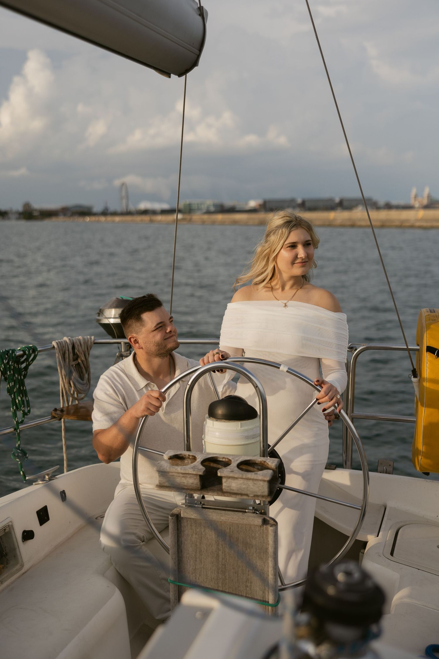 A romantic boat ride with a couple dressed in white sailing along the coastline at sunset.