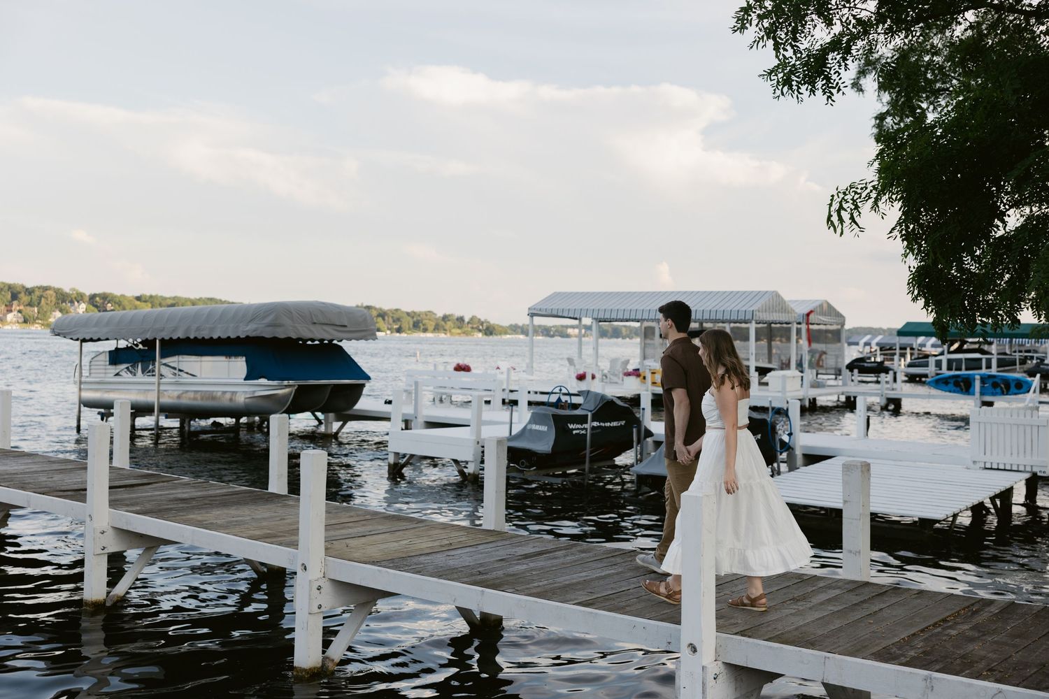Panoramic view of boats docked at a marina with white covered slips stretches across calm waters.