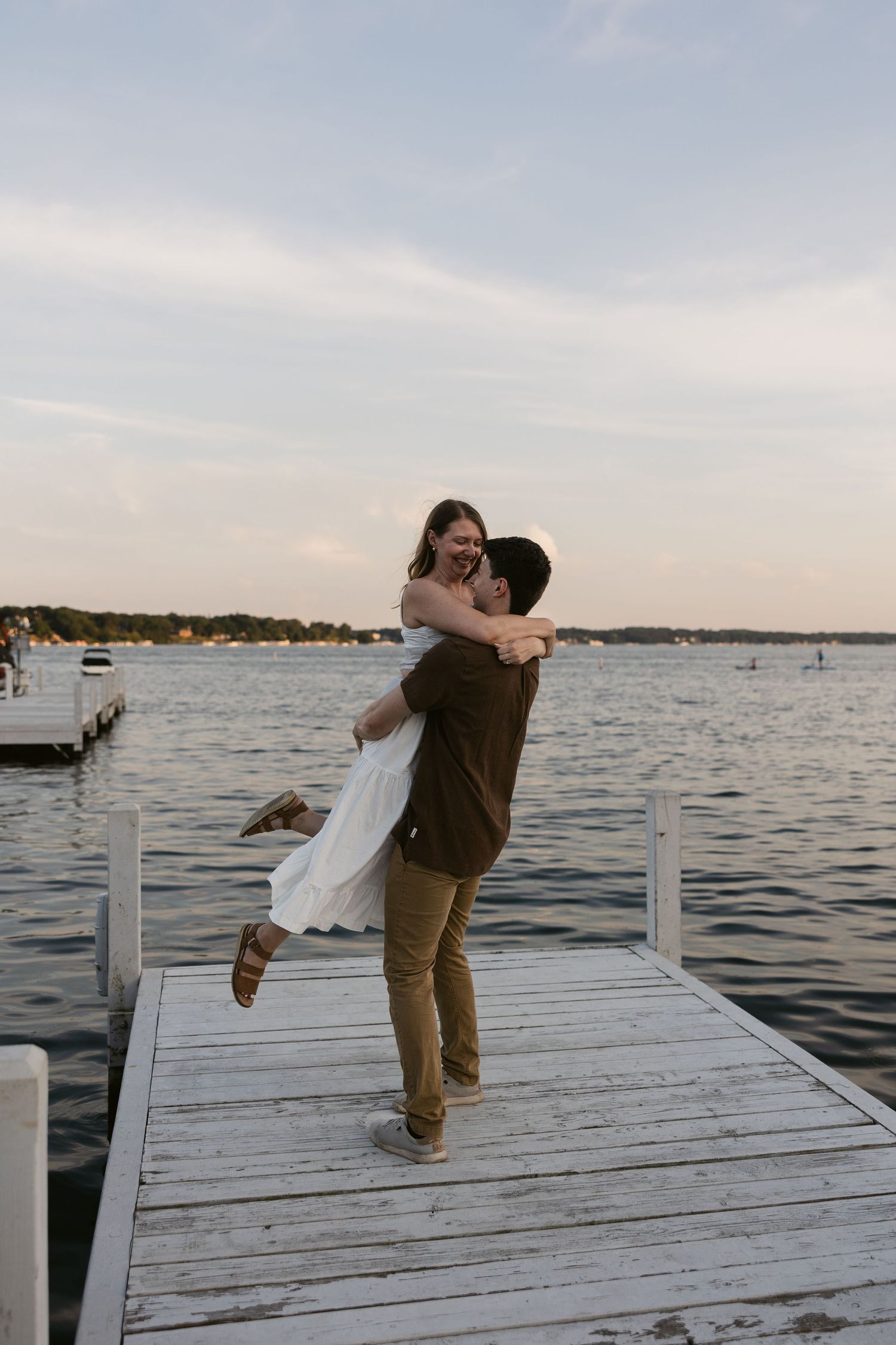 Playful dance moves captured on a lakeside dock during a sunset photoshoot.