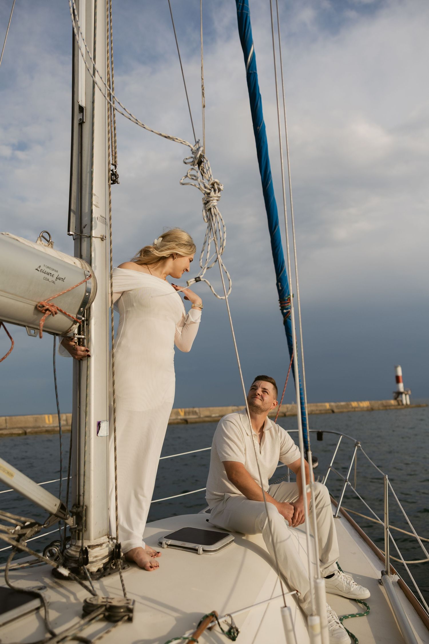 A romantic sailing photoshoot featuring a couple in white outfits enjoying time on a yacht deck.