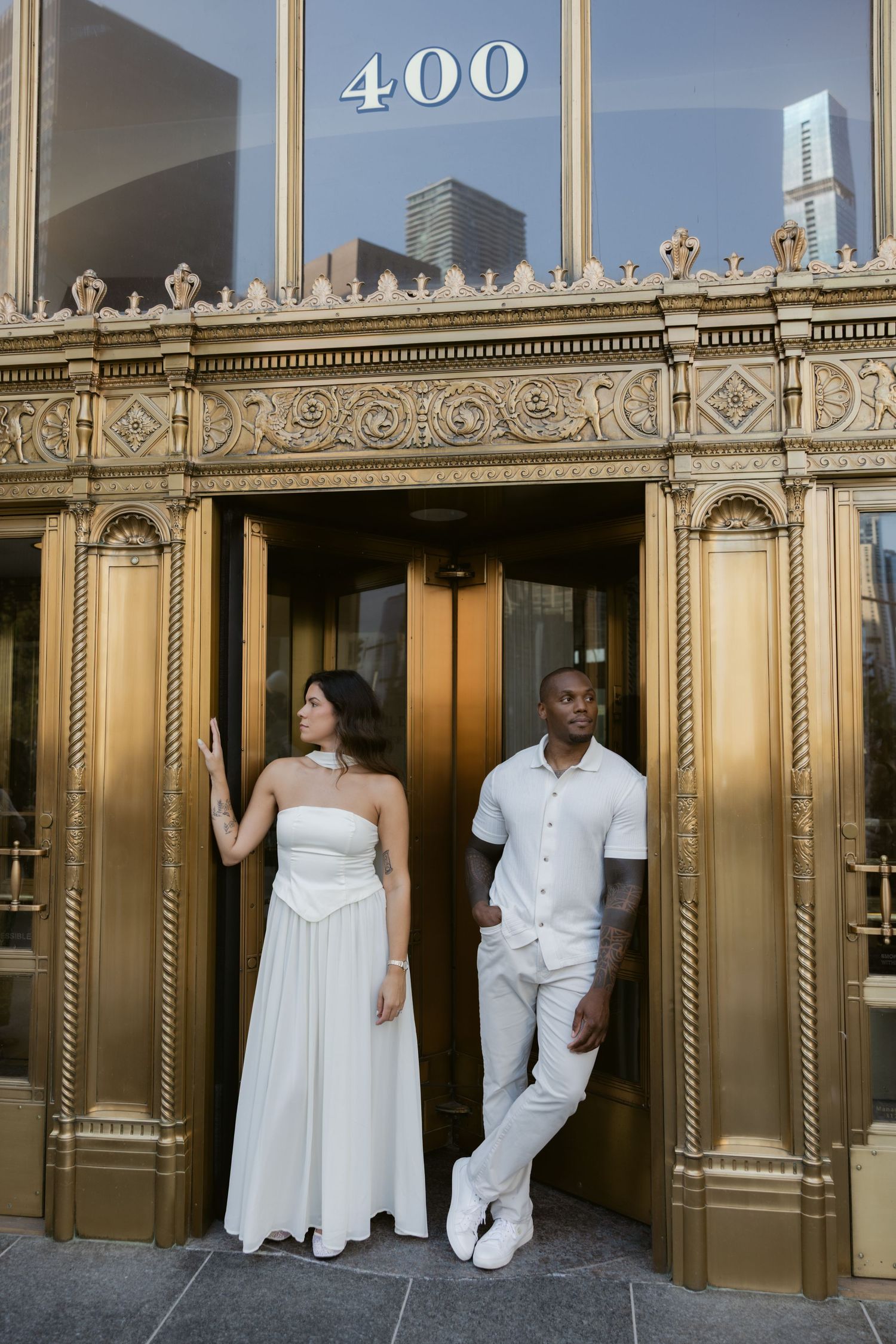 Wedding portraits at an elegant gold-trimmed building entrance marked 400.