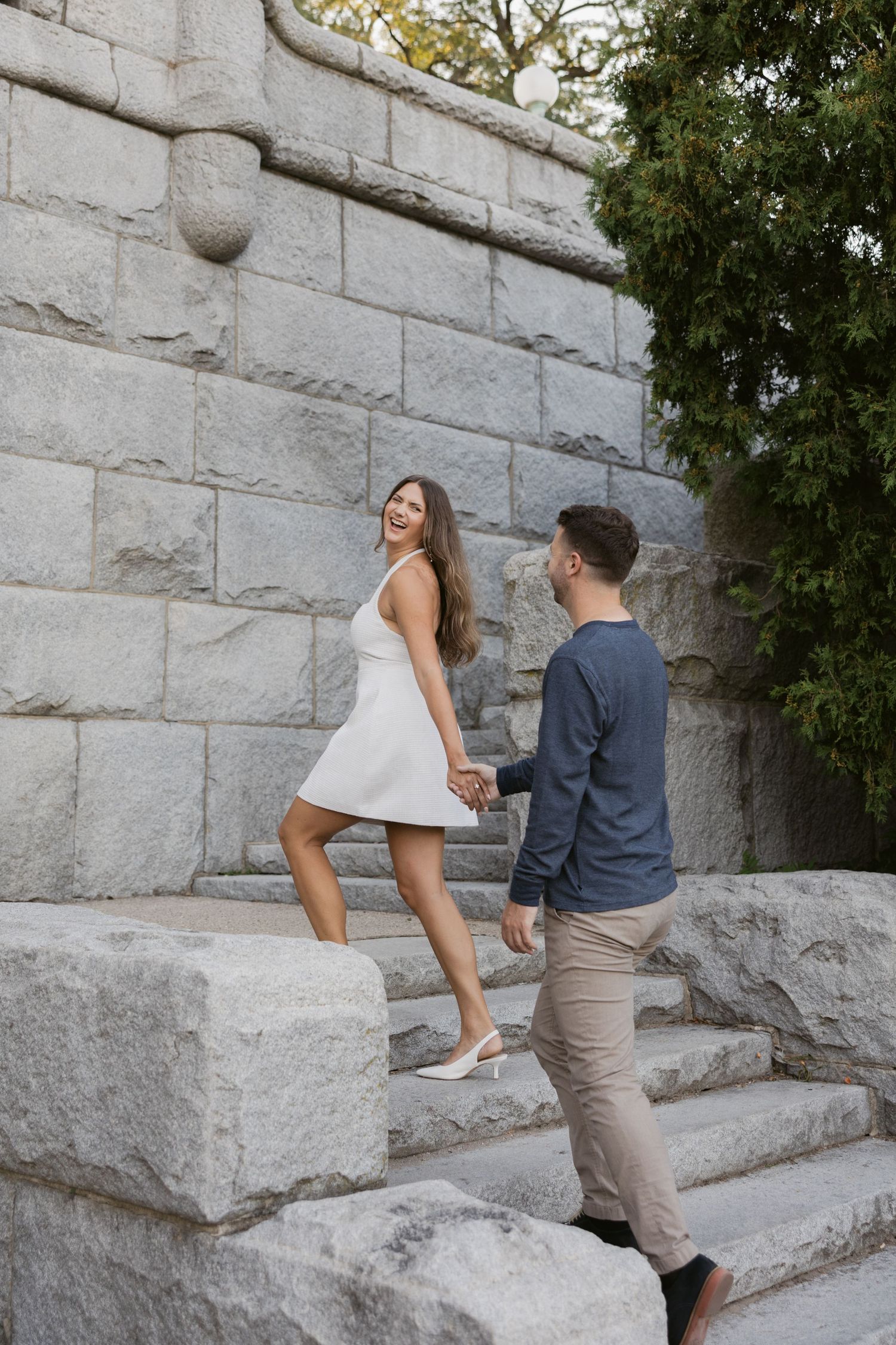 Couple walking up stone steps together in a park setting.