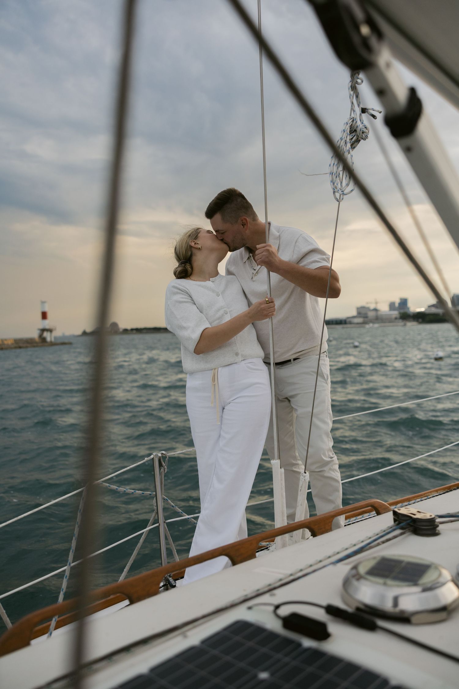 Intimate sailboat photography session with lighthouse visible in the distance.