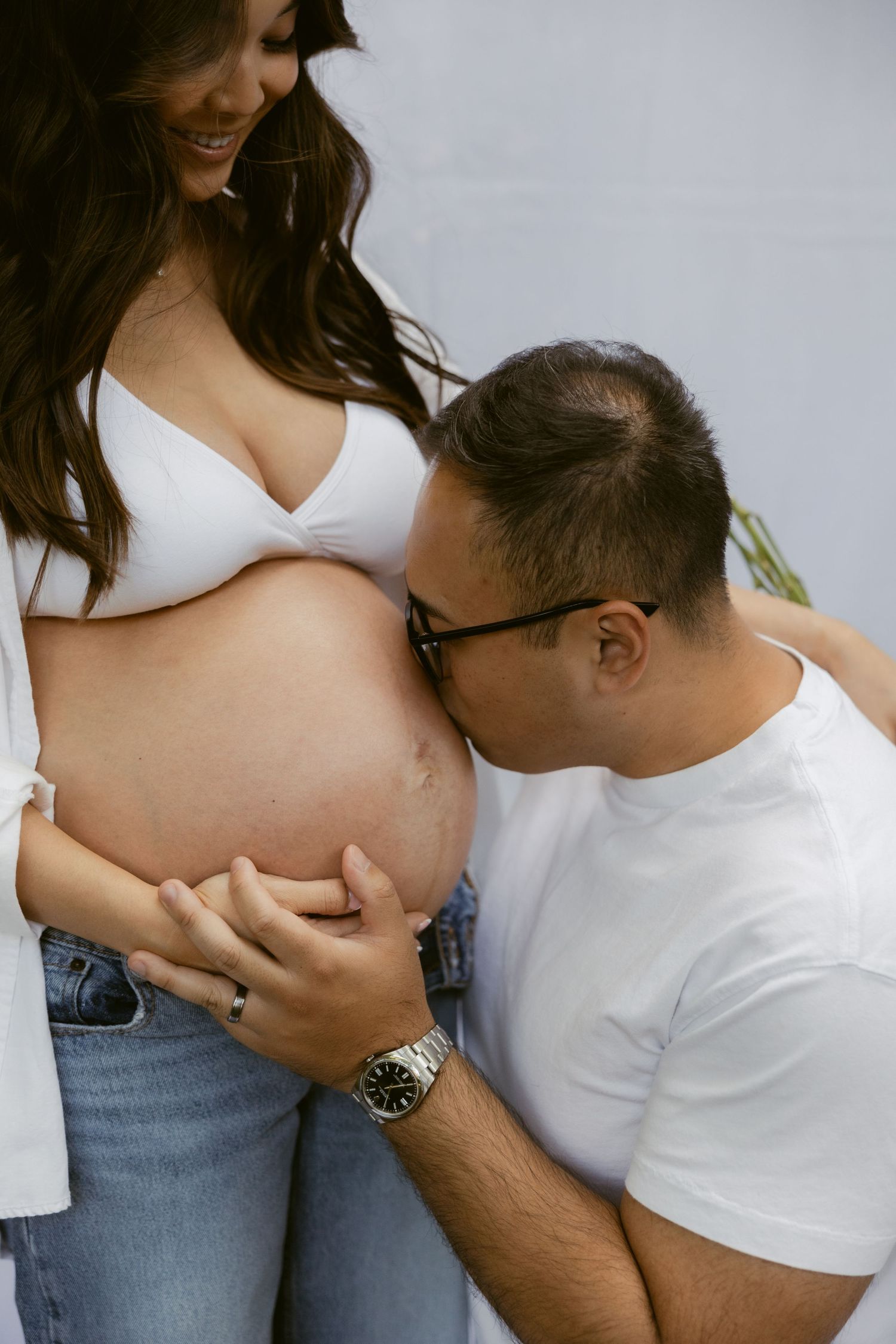 A close-up maternity photograph showing tender moments between an expecting couple.