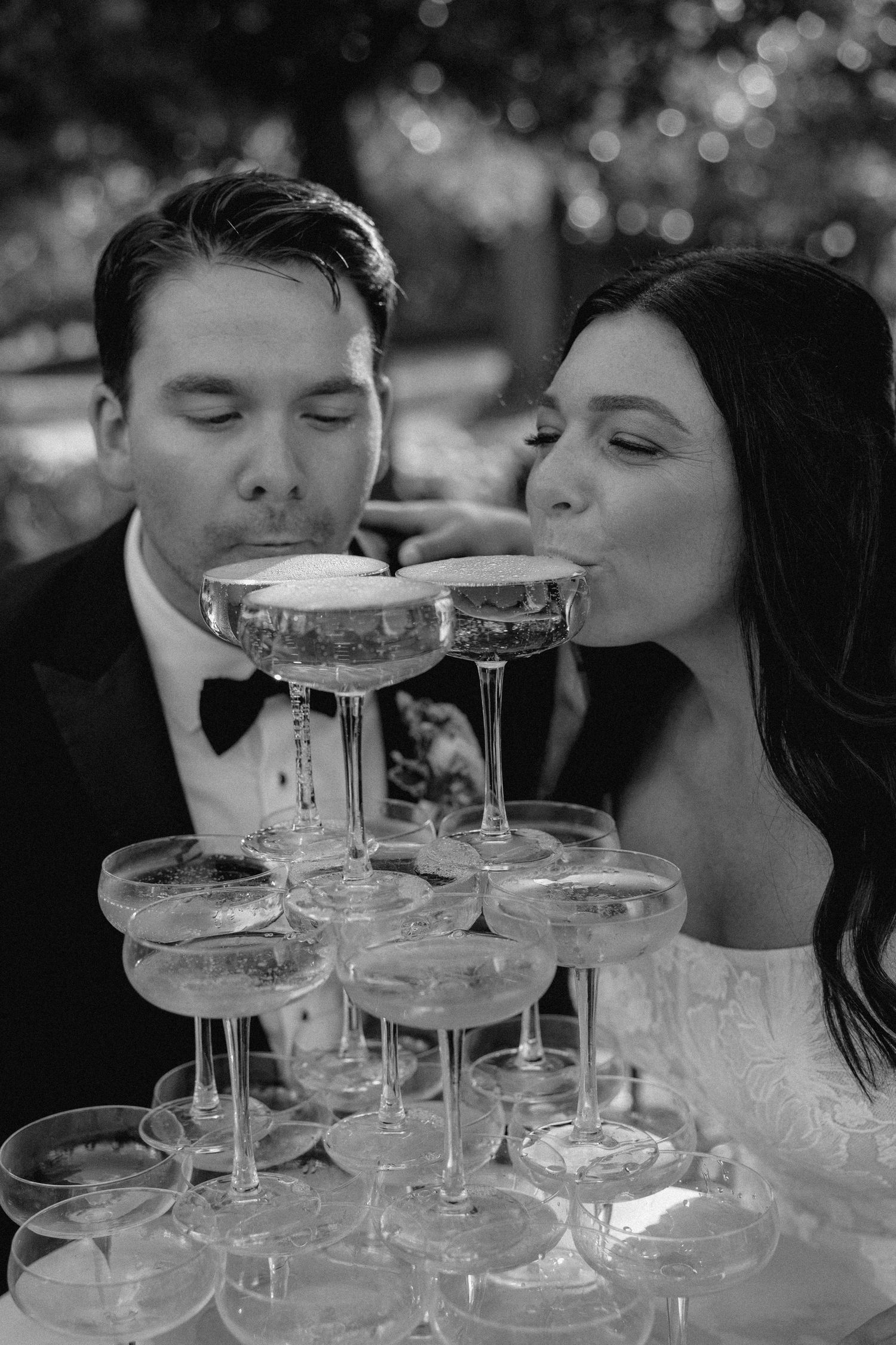 A couple sipping from a champagne tower at an elegant wedding celebration.