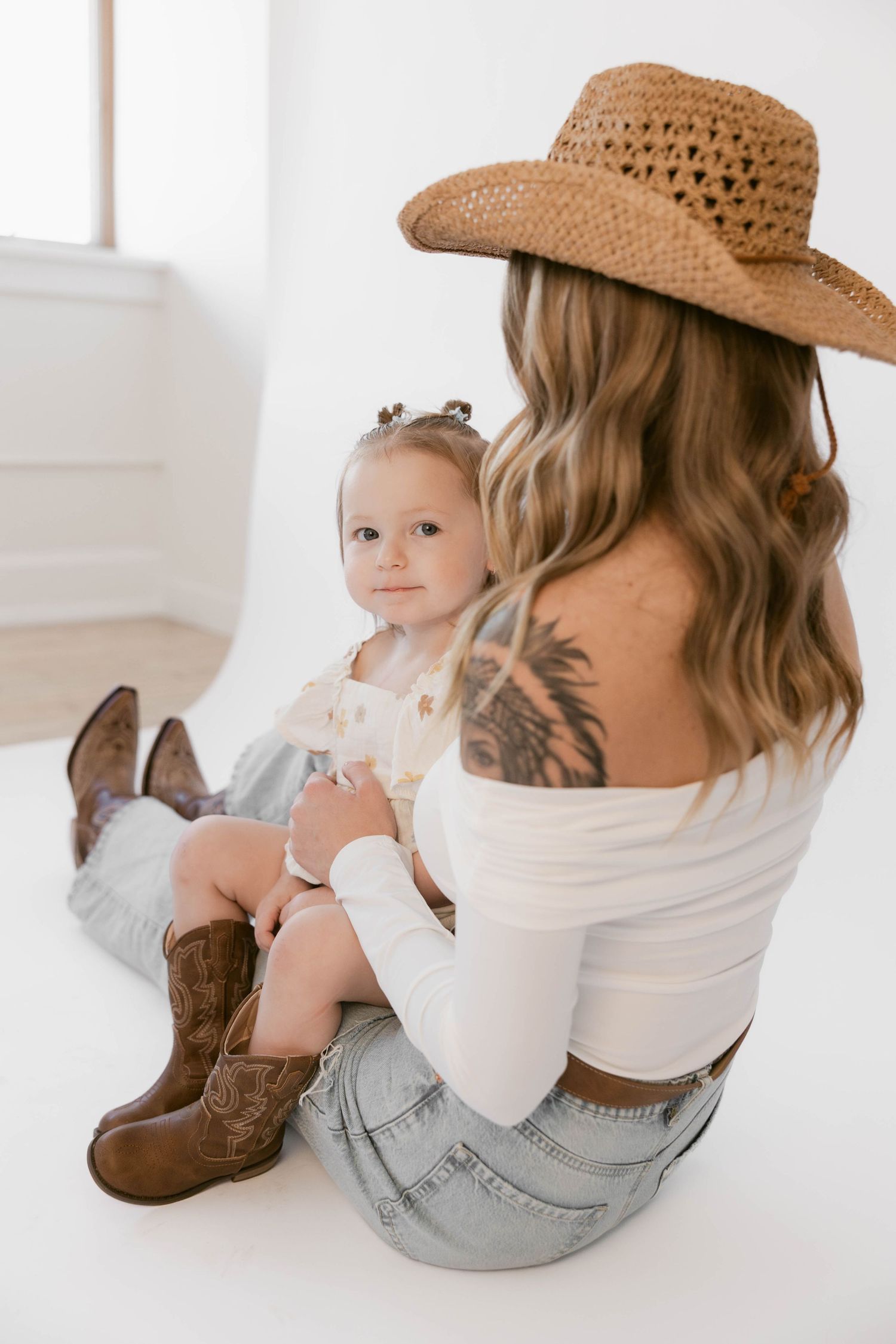 Casual western-themed photo session features denim, cowboy boots and straw hat against white background.