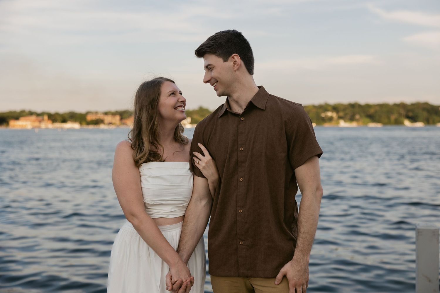 A happy couple shares a joyful moment together by the waterfront at sunset.