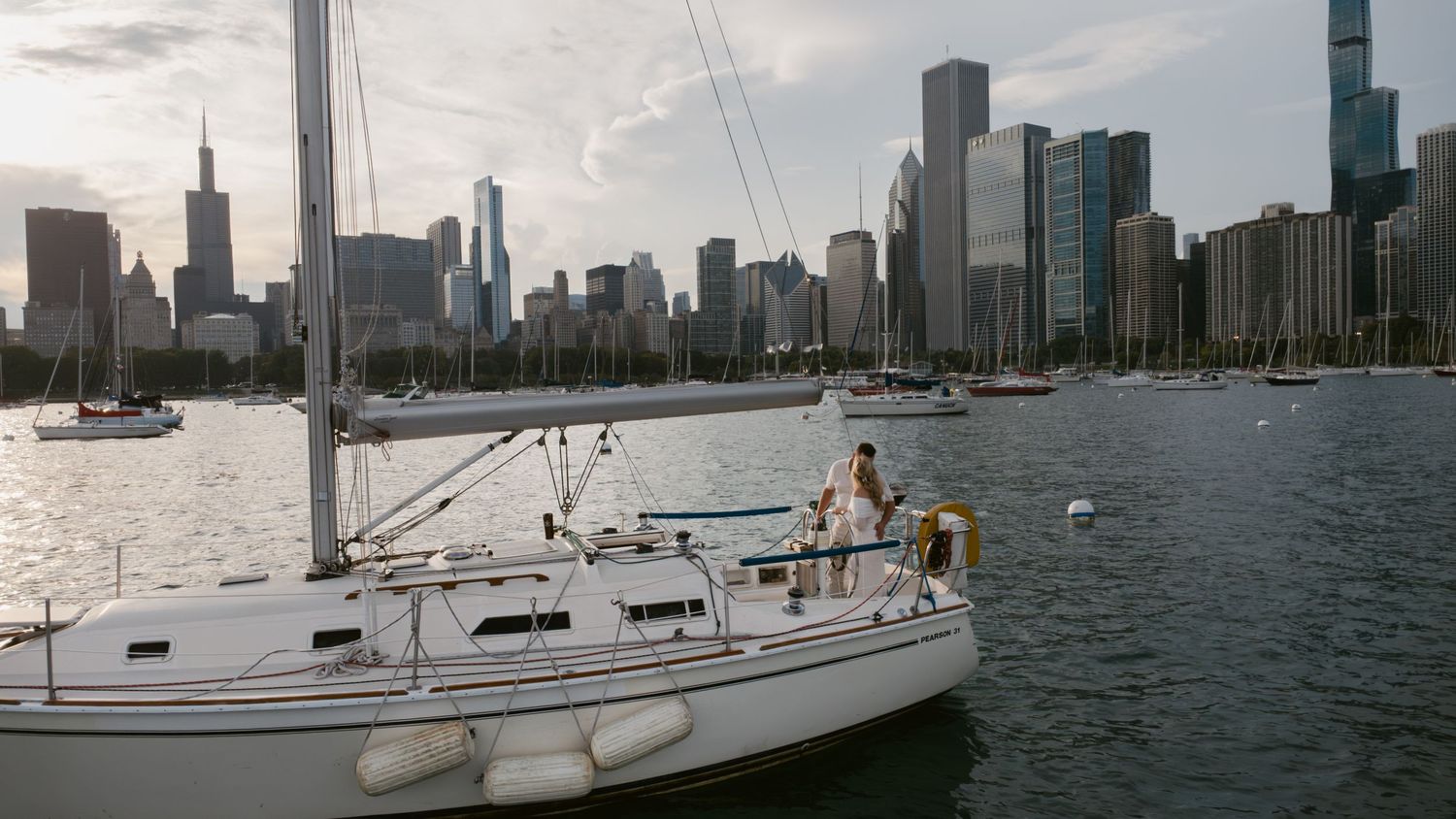 A sailboat cruises along the Chicago waterfront with the dramatic skyline in the background.