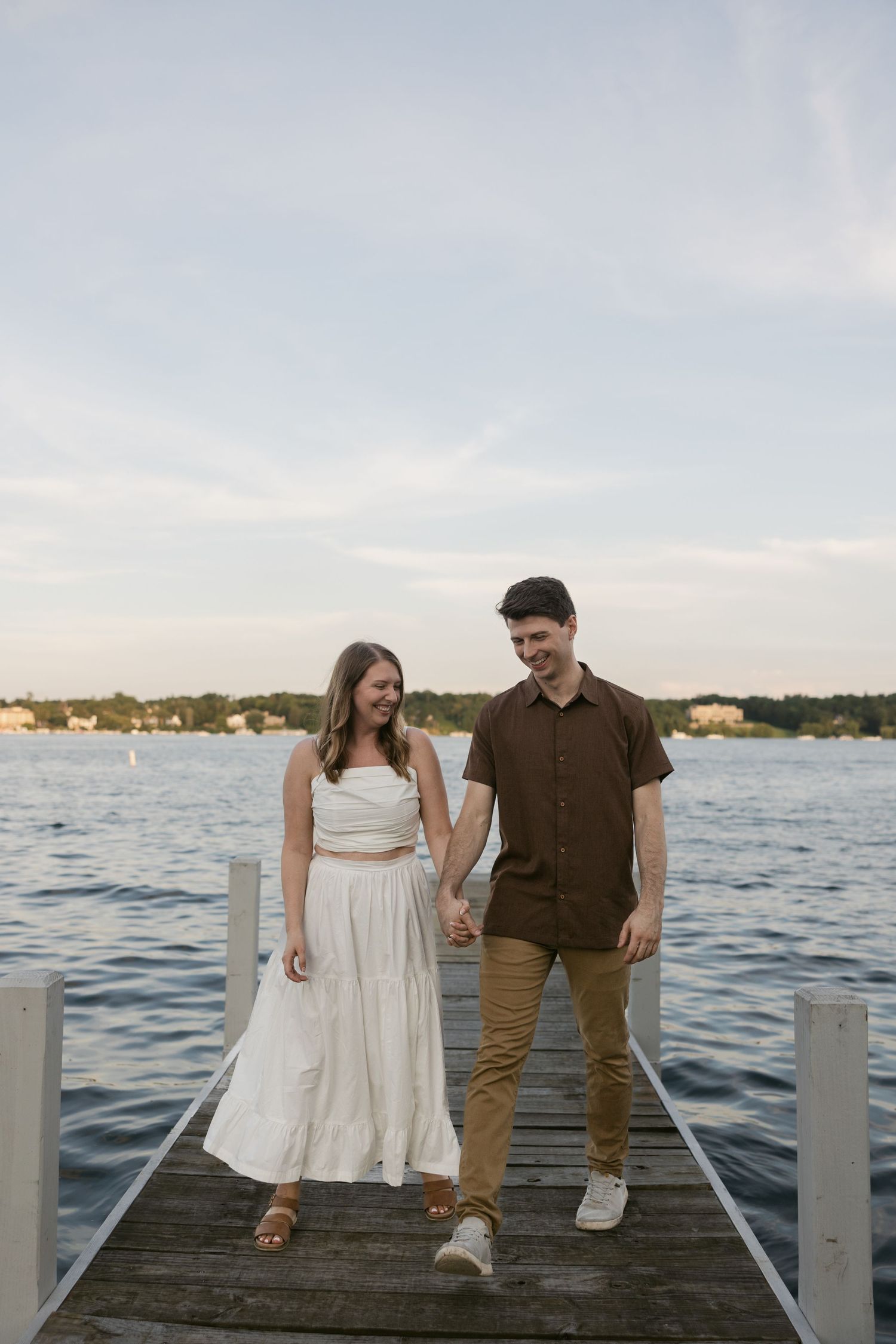 Couple walking together on waterfront pier at dusk in summer attire.