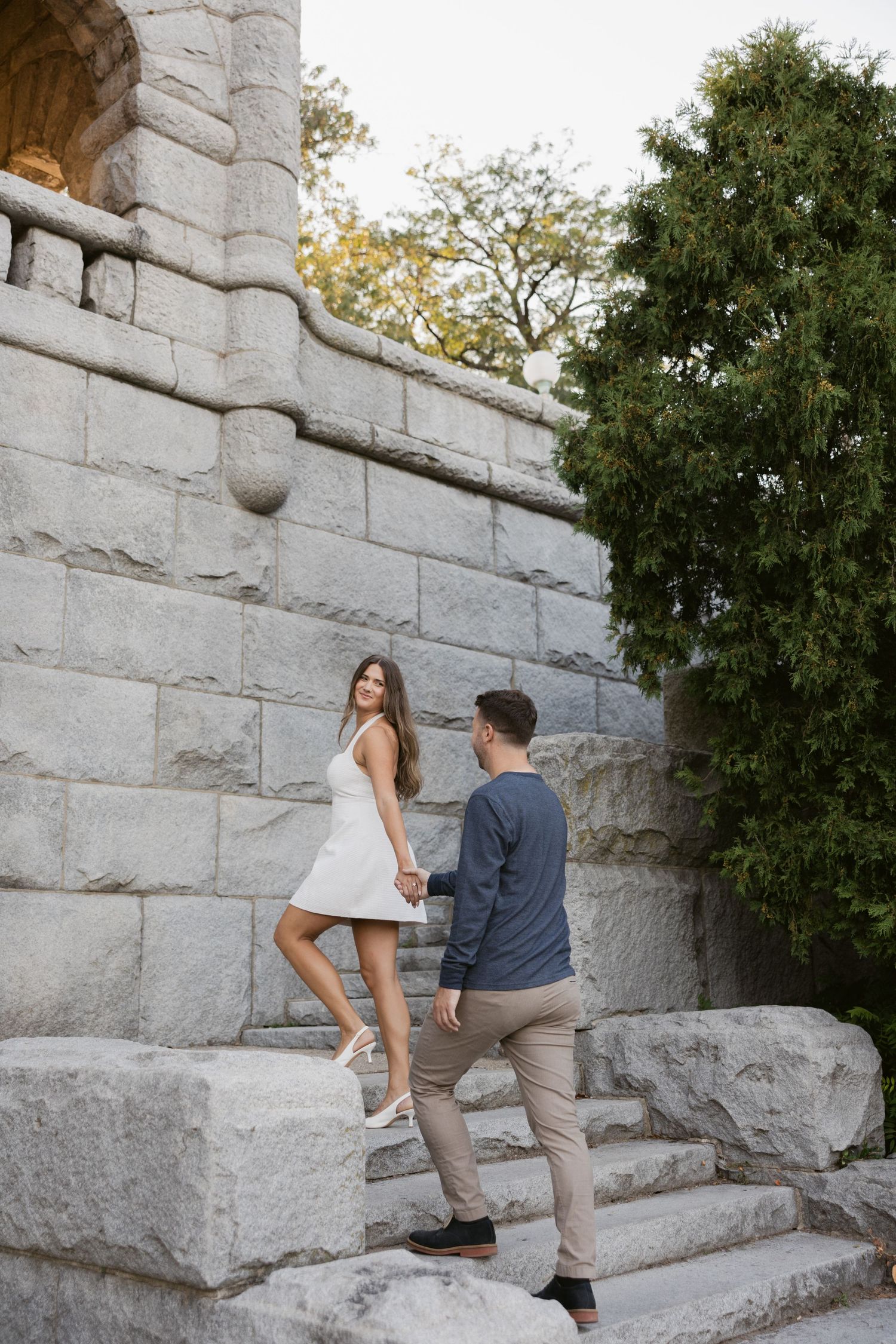 Two people ascending stone steps in a park with natural greenery backdrop.