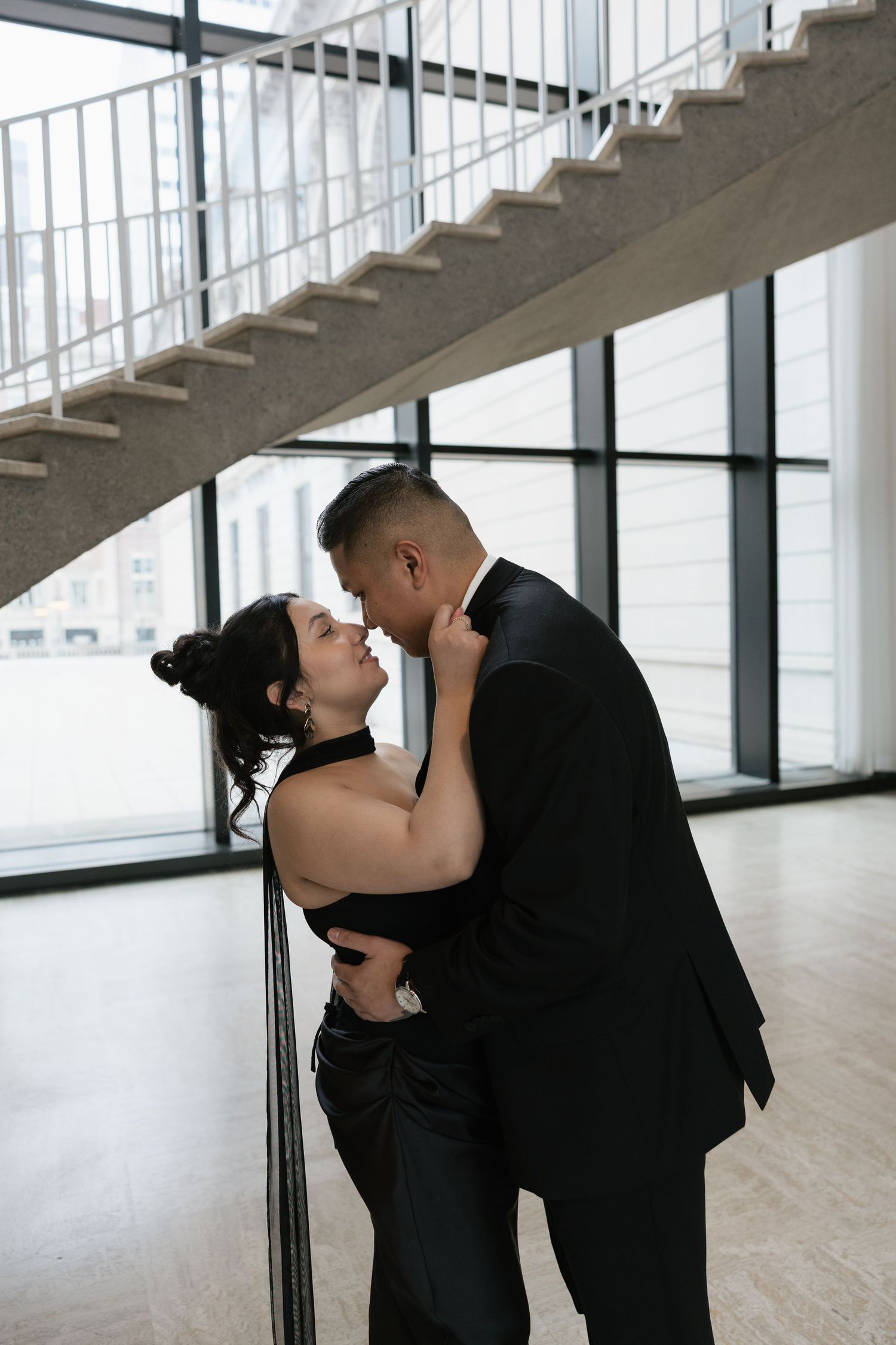 A couple embraces in a modern minimalist space with white walls and concrete floors.