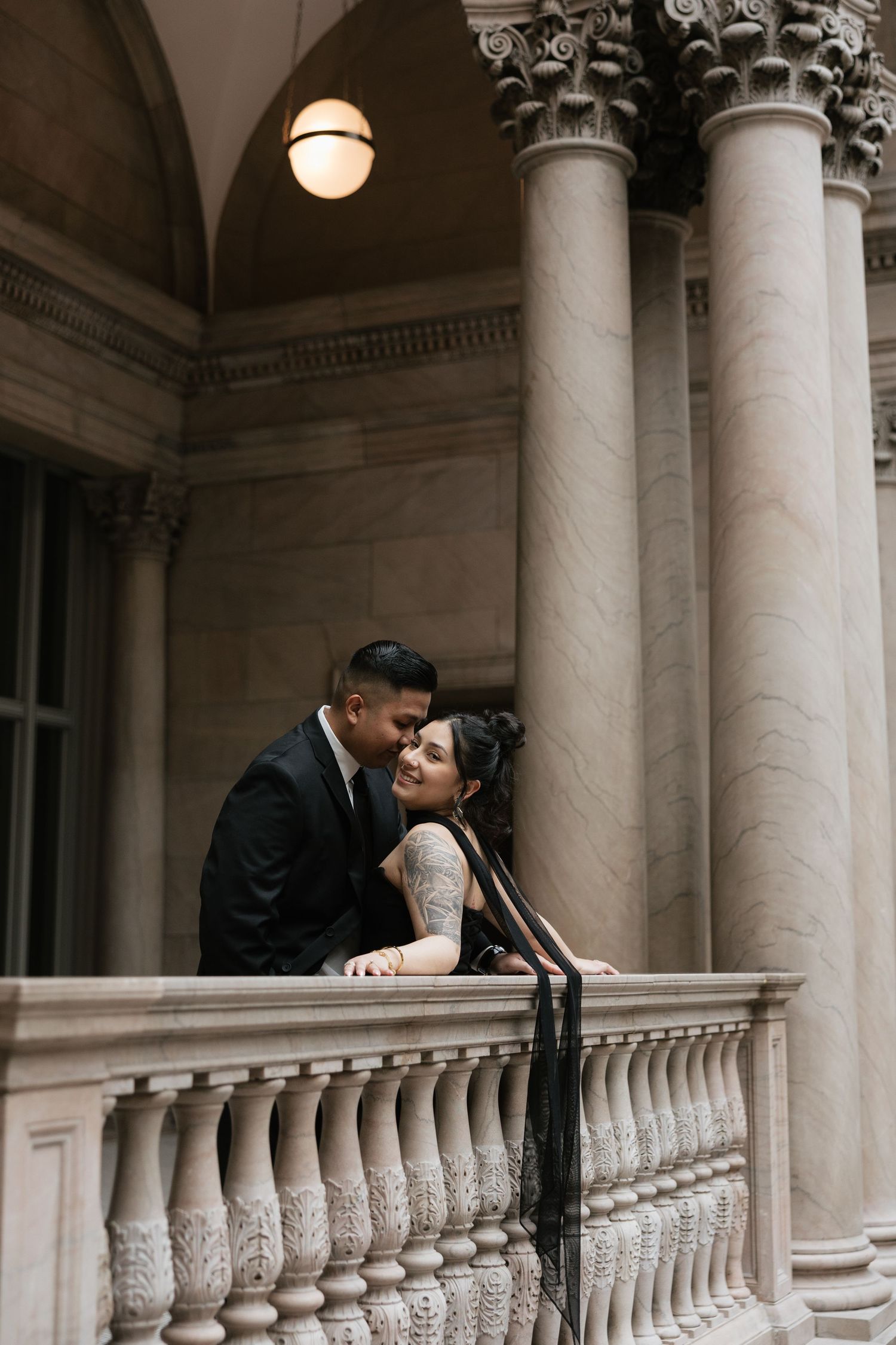 A romantic moment captured between a couple at a grand marble colonnade with ornate architectural details.