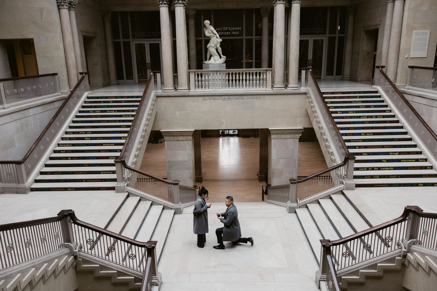 A grand marble staircase with ornate railings in a classical architectural space.