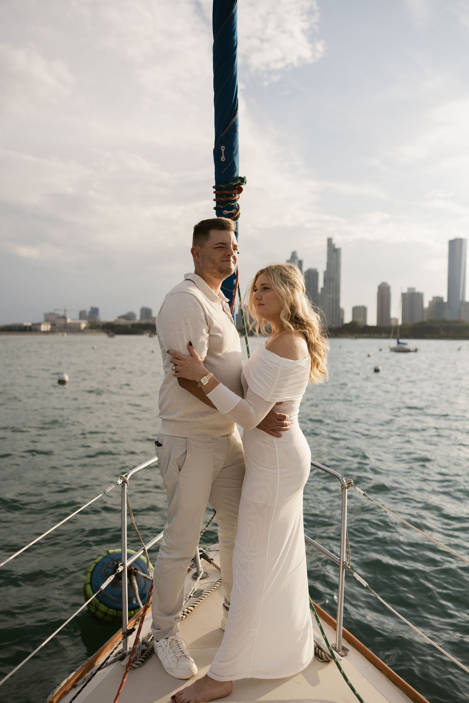 A couple enjoys a romantic moment on a sailboat with the Chicago skyline visible across Lake Michigan.