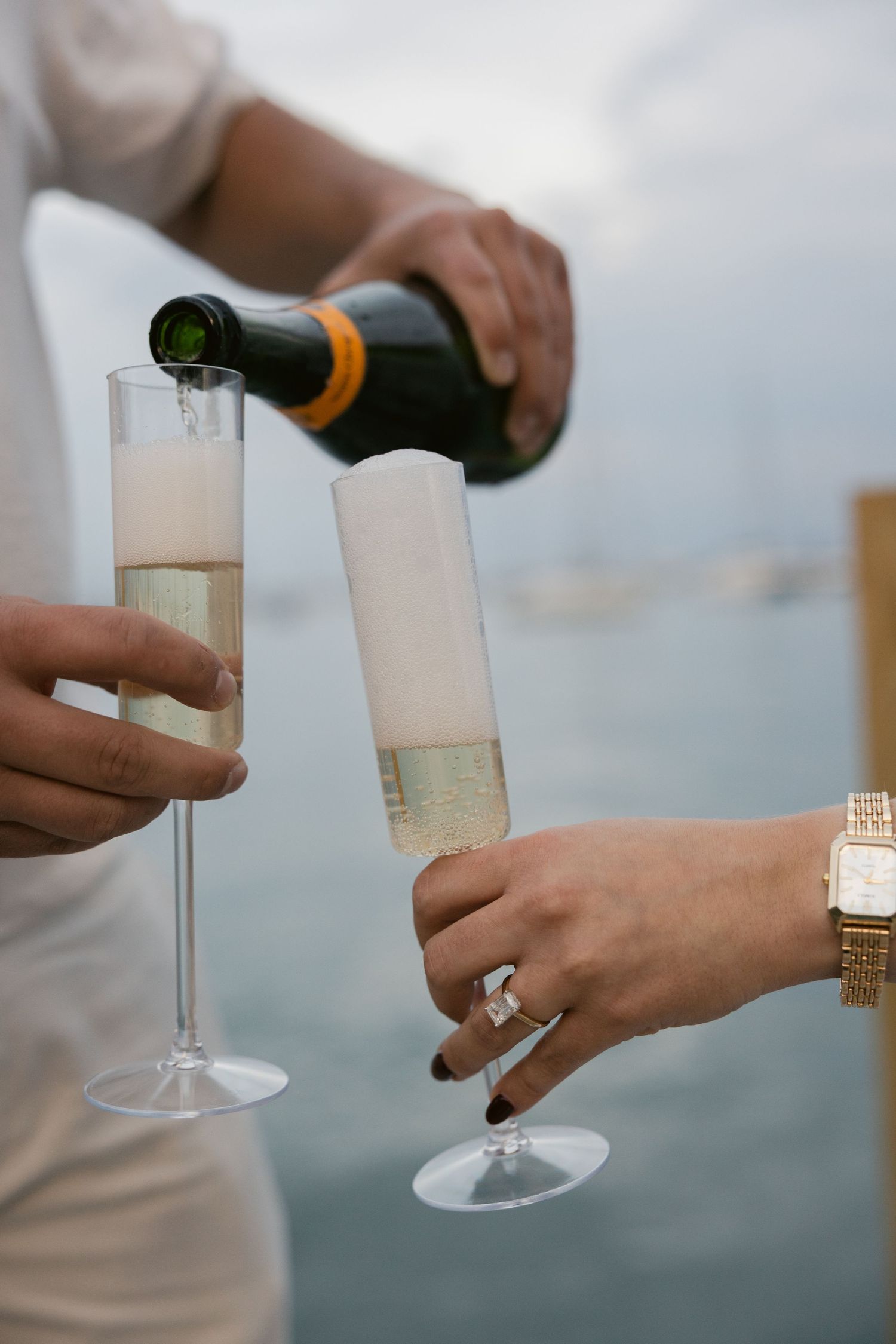 Champagne being poured into glasses on a boat with the city skyline in the background.