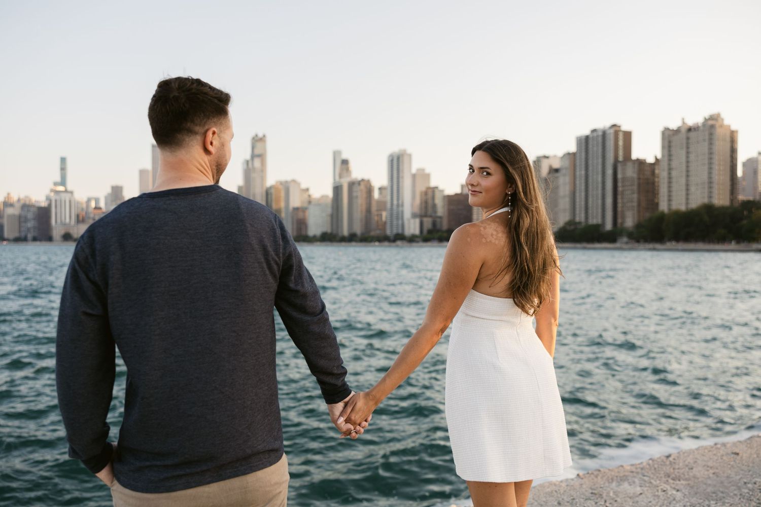 A couple strolls along Chicago's waterfront with the iconic skyline visible in the background.