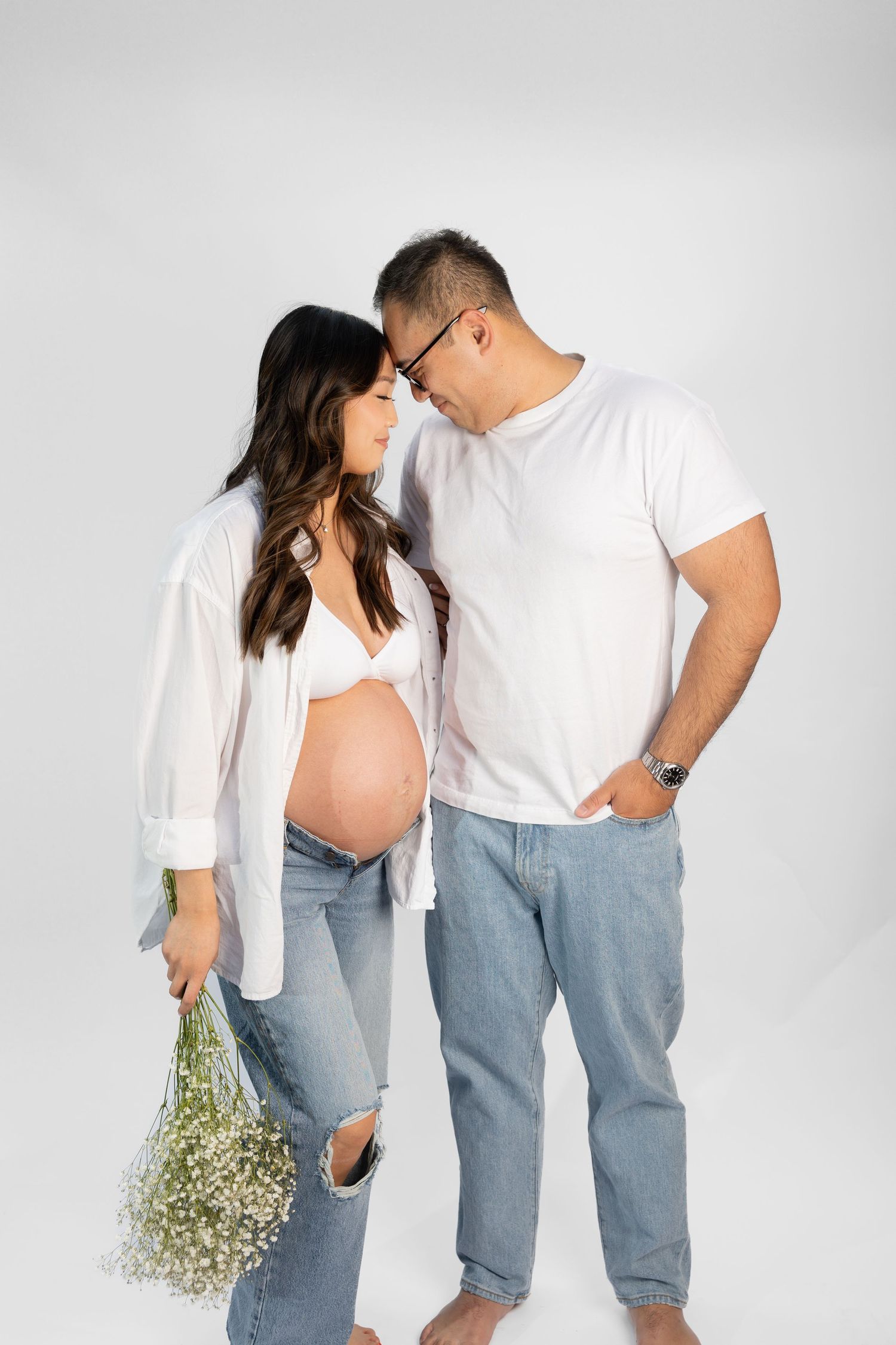 Couple in casual white and denim share intimate moments in studio setting.