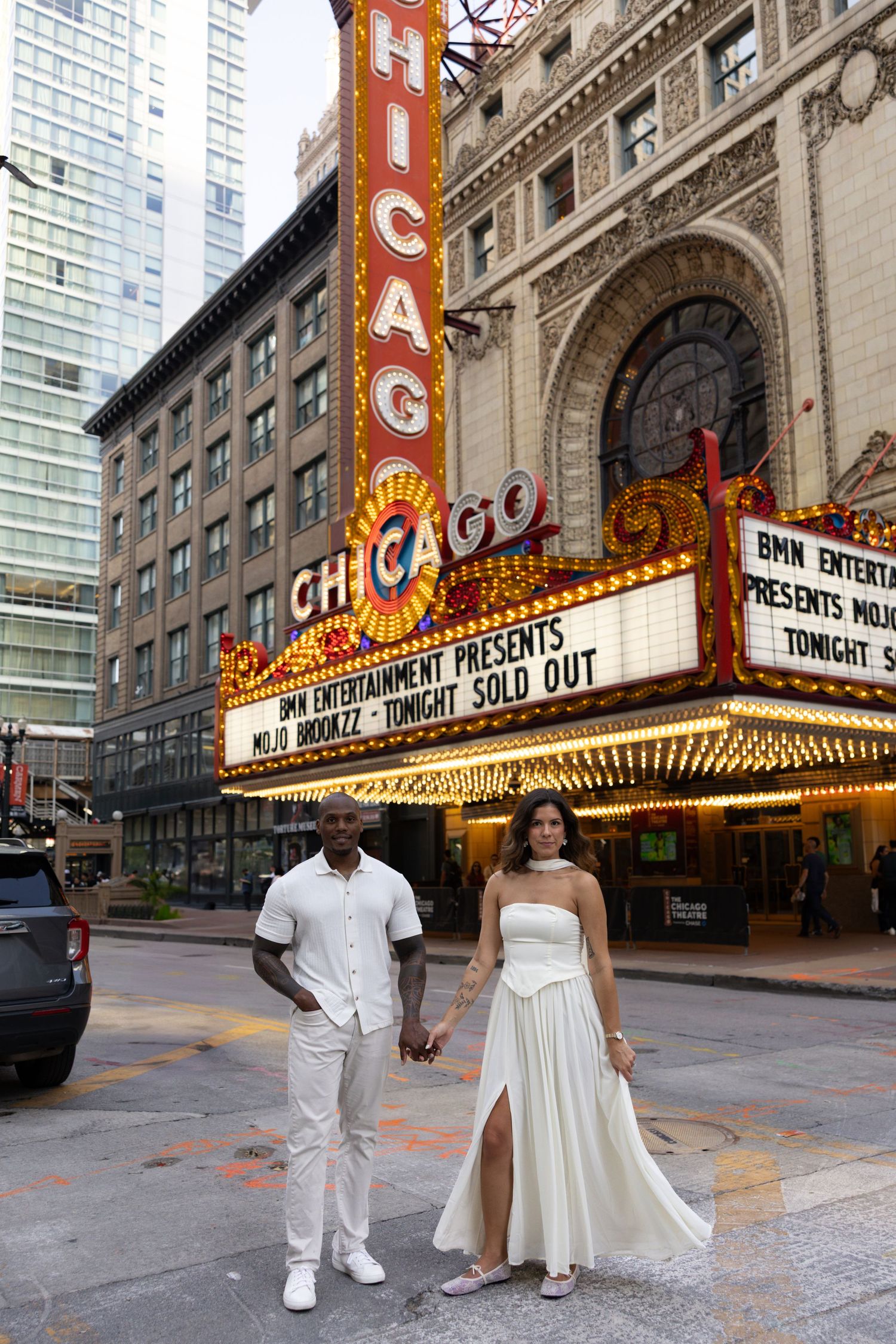 A couple poses outside the historic Chicago Theatre with its iconic illuminated marquee.