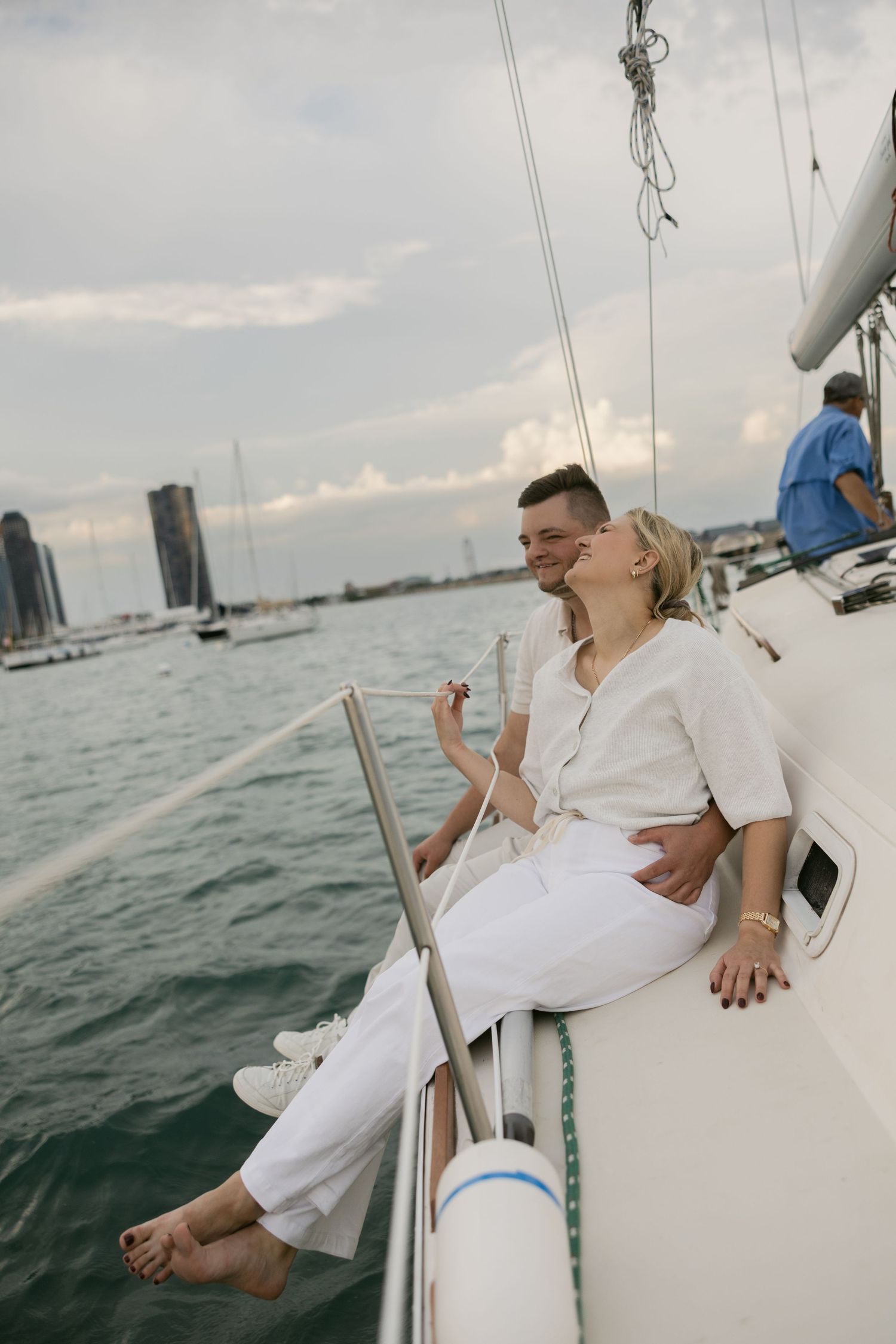 Relaxed couple lounging on sailboat deck with cityscape views.