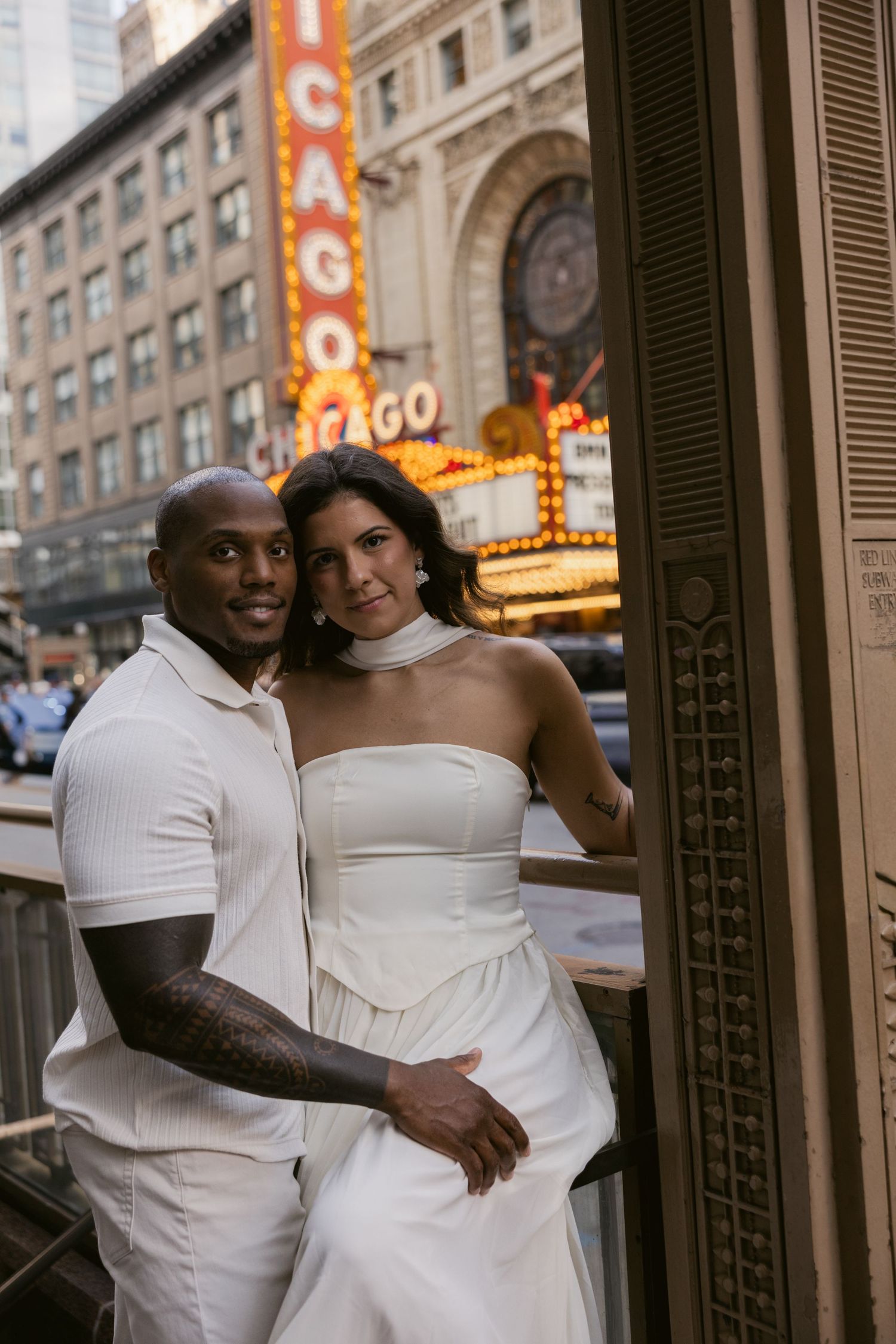 A couple poses together outside a historic Chicago theater with vintage marquee signs visible.