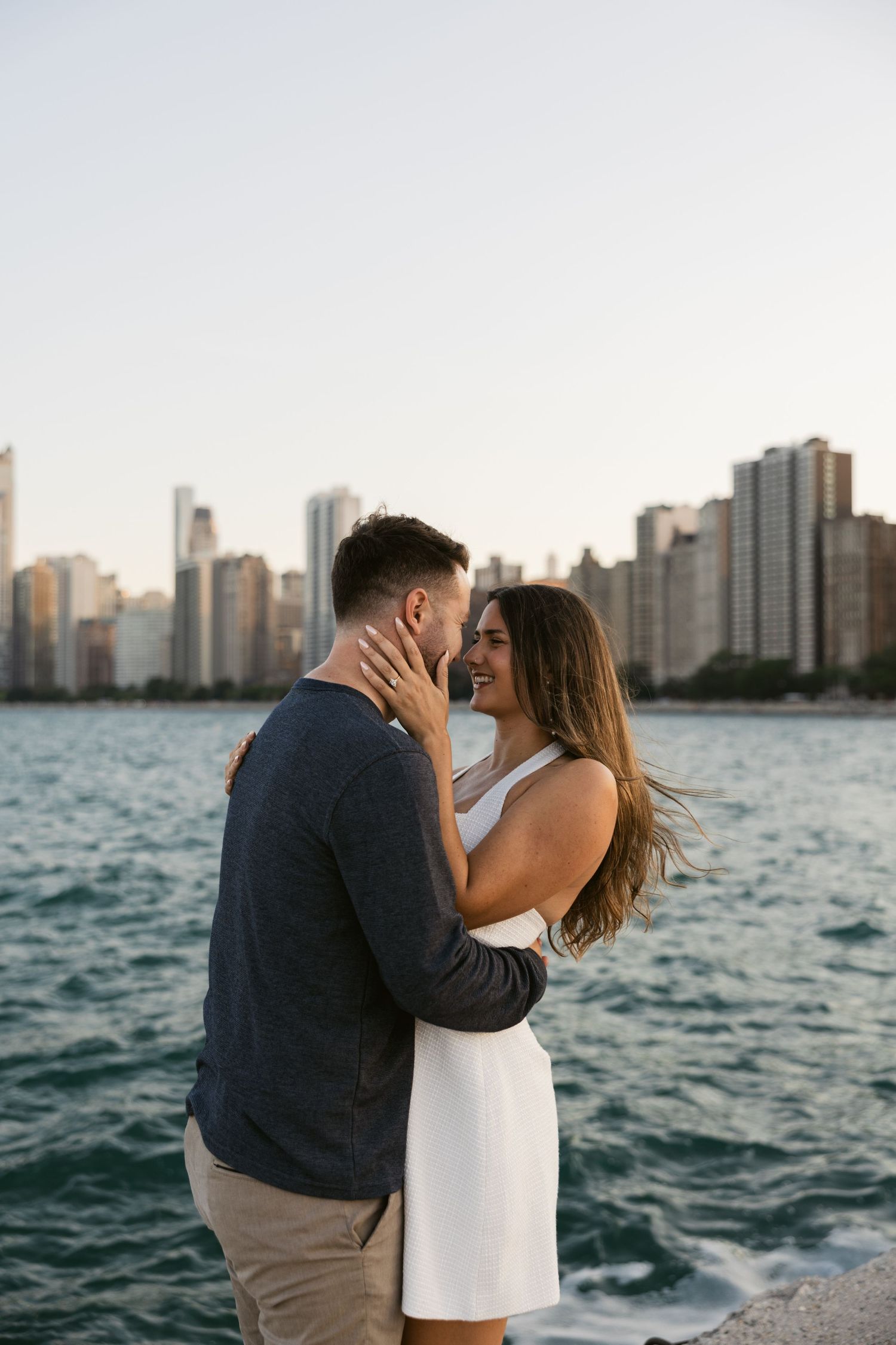 Romantic couple embracing at sunset with Chicago skyline and Lake Michigan in background.