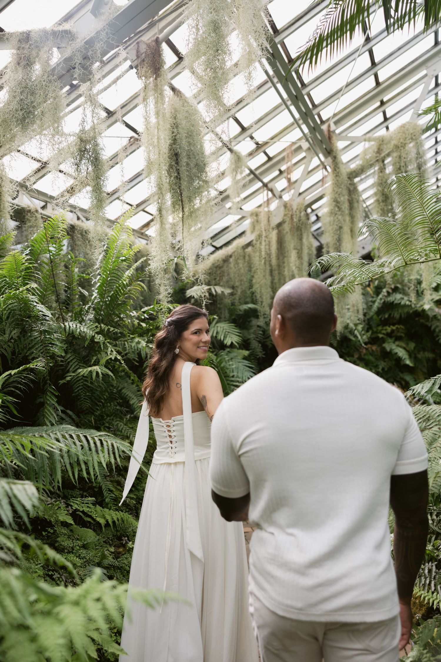 An intimate moment captured in a greenhouse with hanging Spanish moss and tropical plants.
