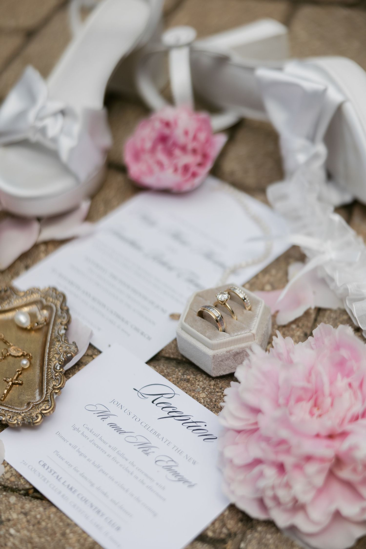 Elegant wedding invitations with pink carnations and gold details arranged on a rustic surface.