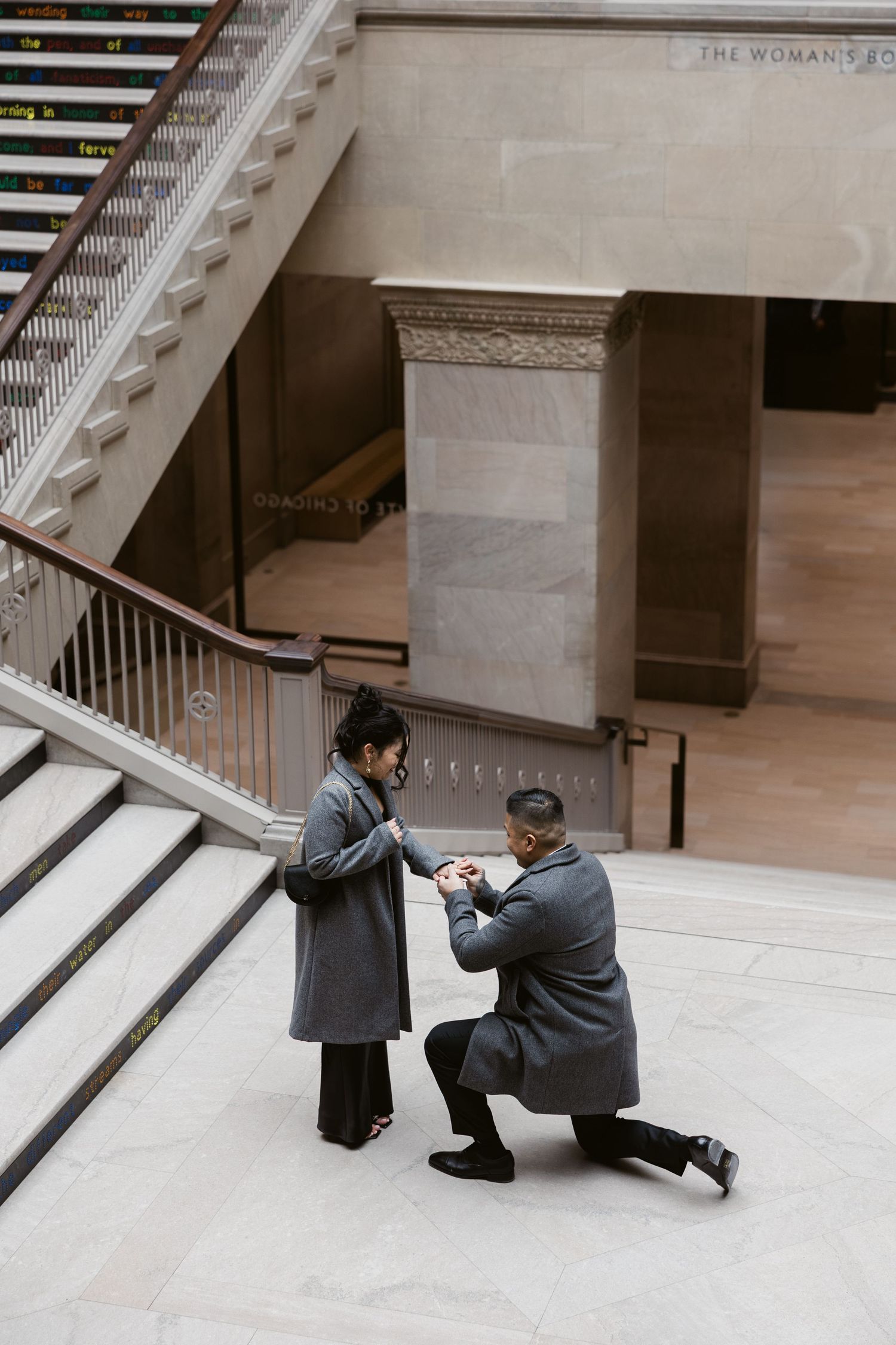 A proposal moment captured on marble steps in an elegant building interior.