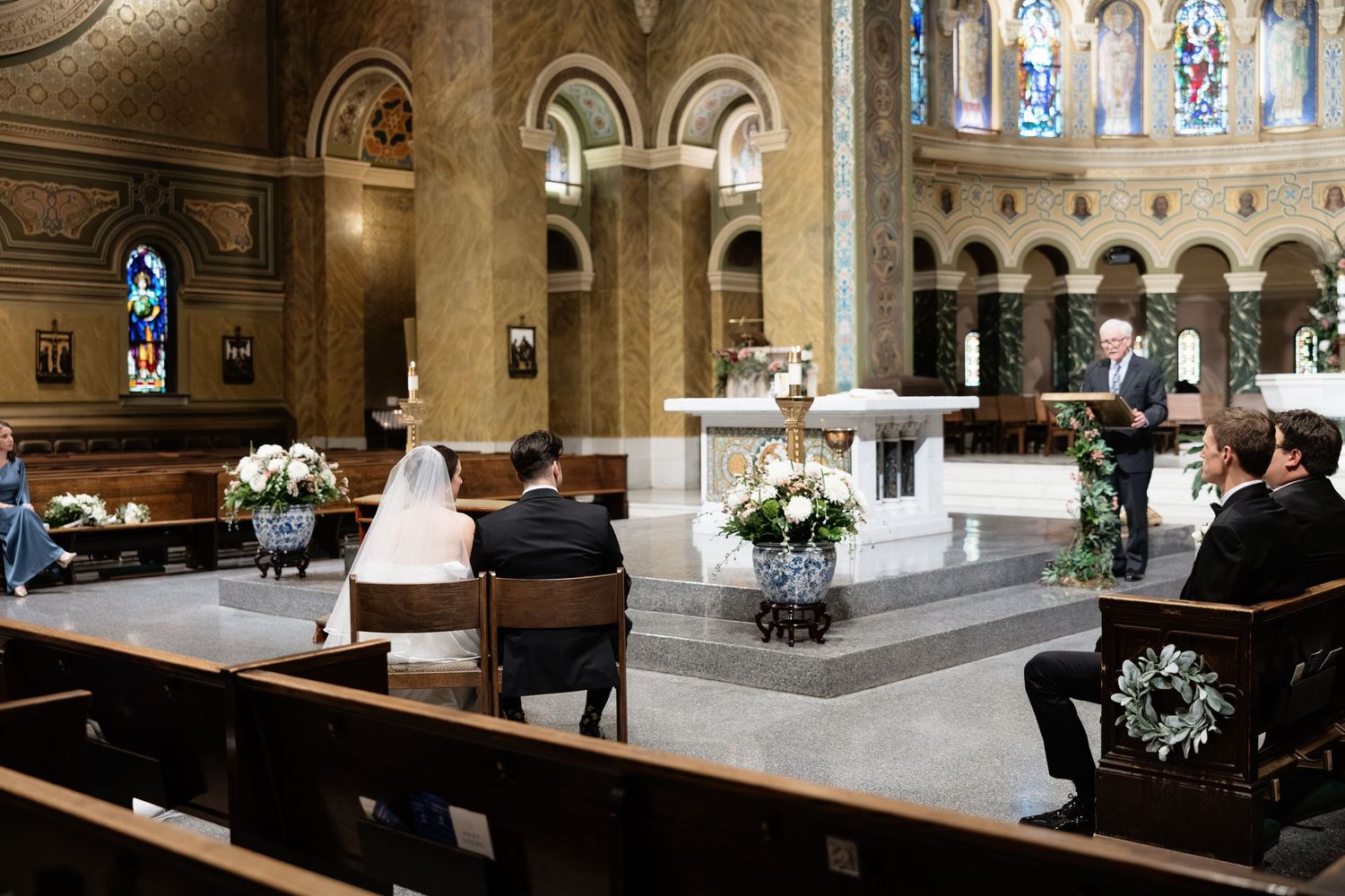 Elegant church interior with ornate stained glass windows, arched ceilings, and wooden pews illuminated by natural light.