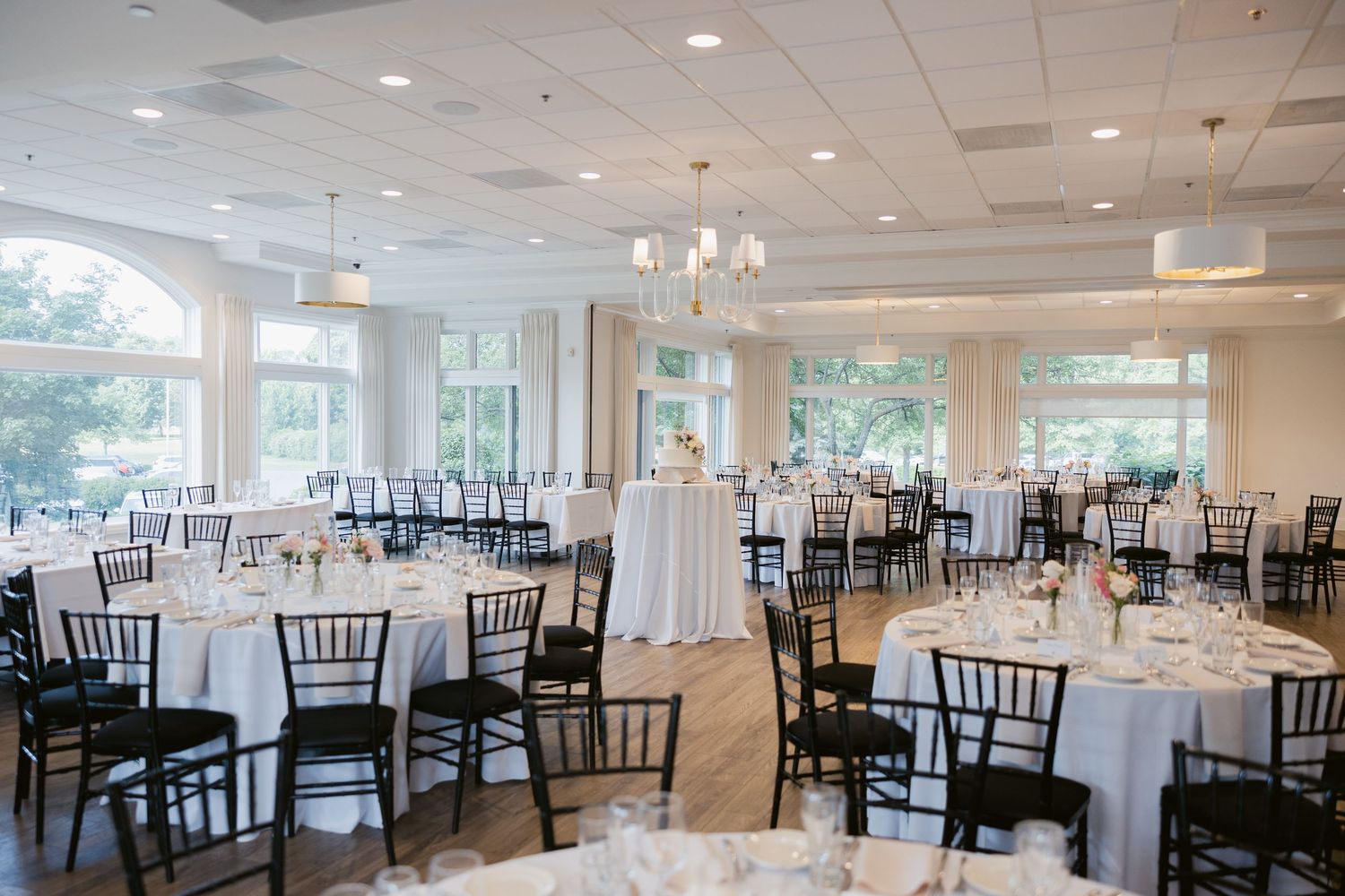 Elegant wedding reception venue with round tables, white linens and black chiavari chairs.