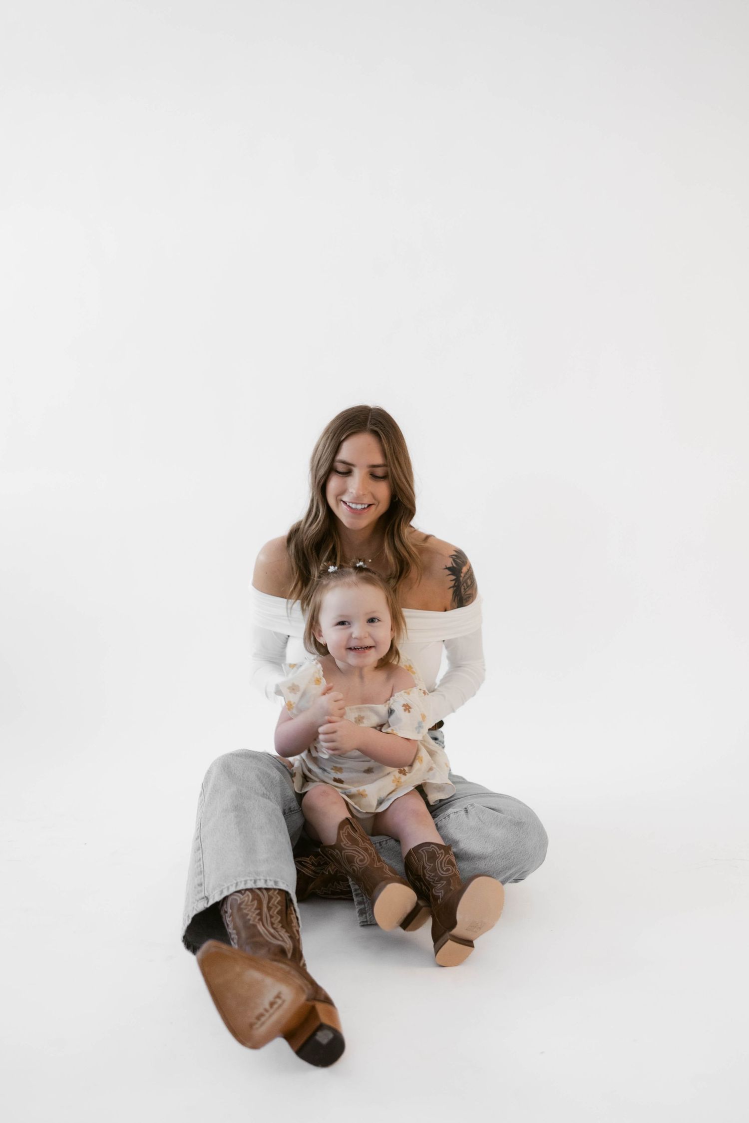 Studio portrait on white background with matching brown boots and casual styling.