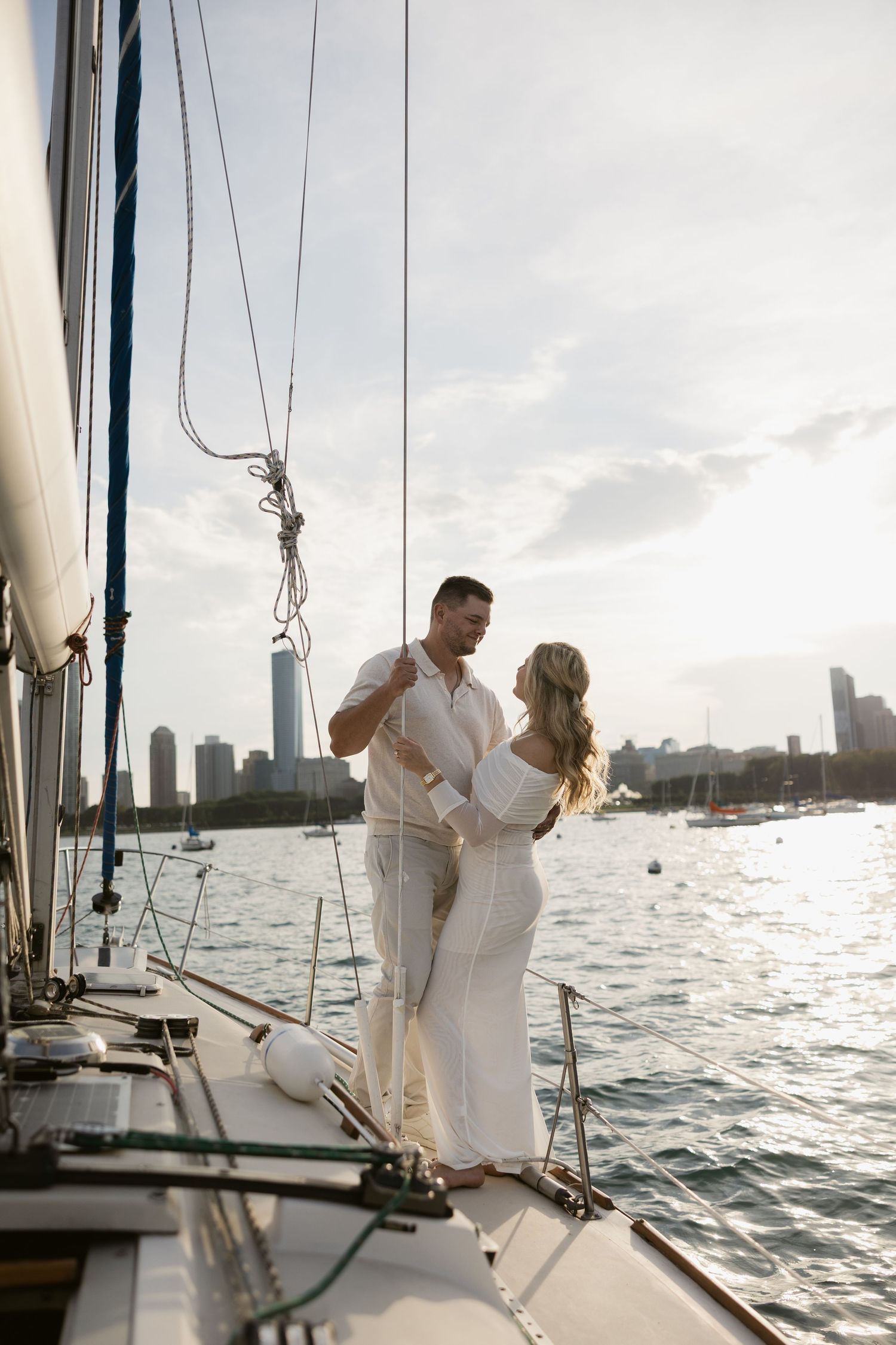 Intimate moments captured on a sailboat deck against dramatic urban waterfront backdrop.
