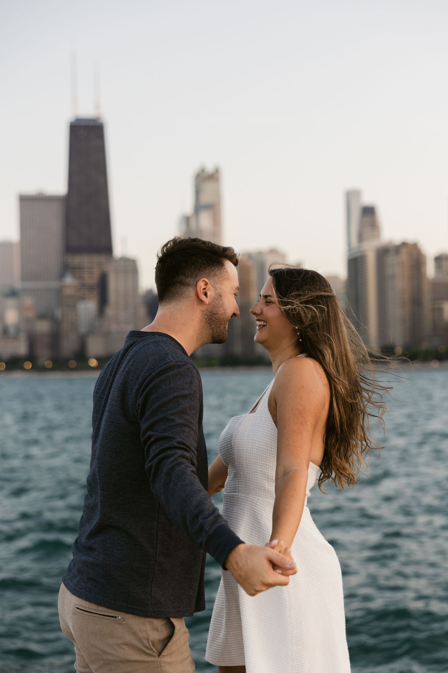 A couple embraces along Lake Michigan with Chicago's iconic skyline in the background.