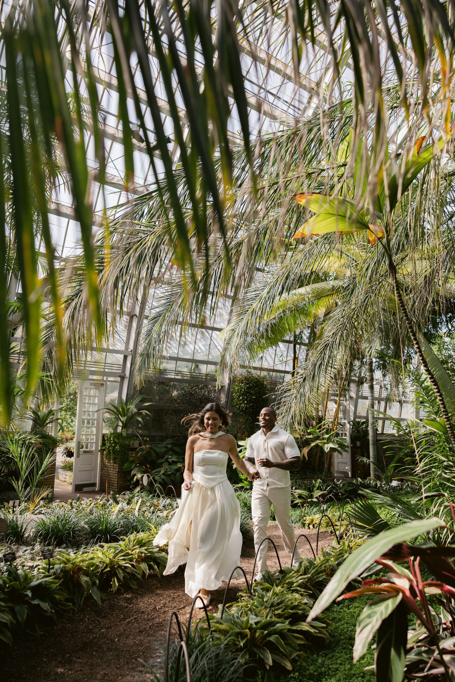 Romantic photo session in a tropical greenhouse with palm fronds and natural light.