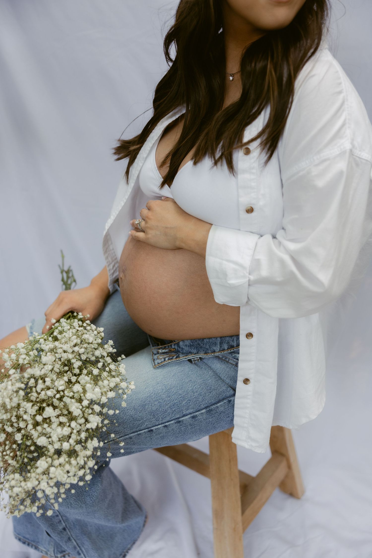 Minimalist maternity photos with baby's breath flowers and casual styling.