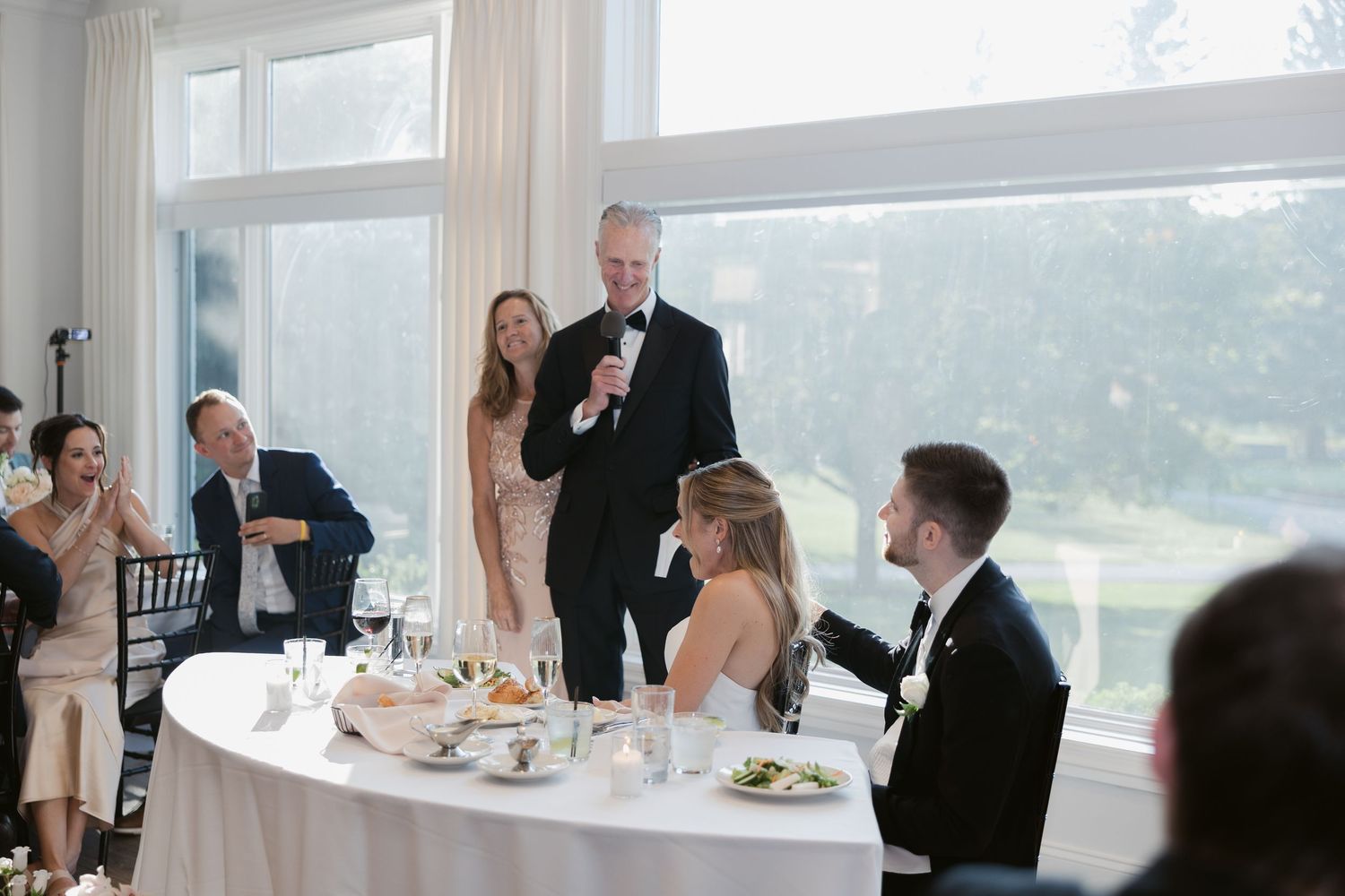 Elegant indoor wedding reception featuring bright windows and formal table settings.