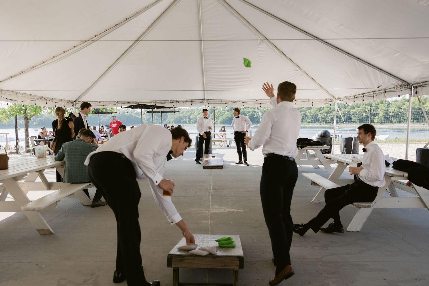 Event staff setting up tables under a white tent for a wedding reception.