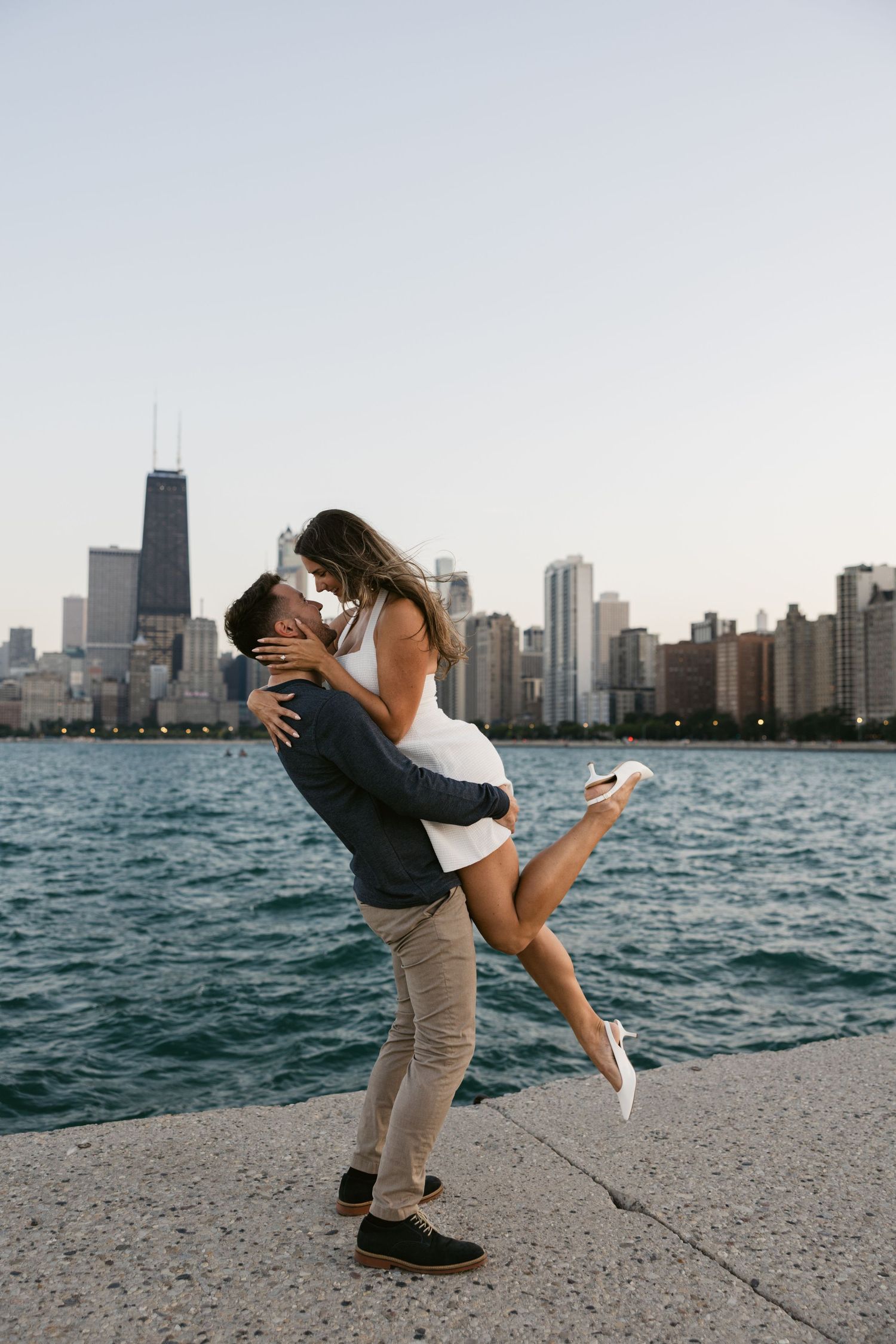 Playful couple dancing and dipping on a lakefront path with Chicago's skyline behind them.