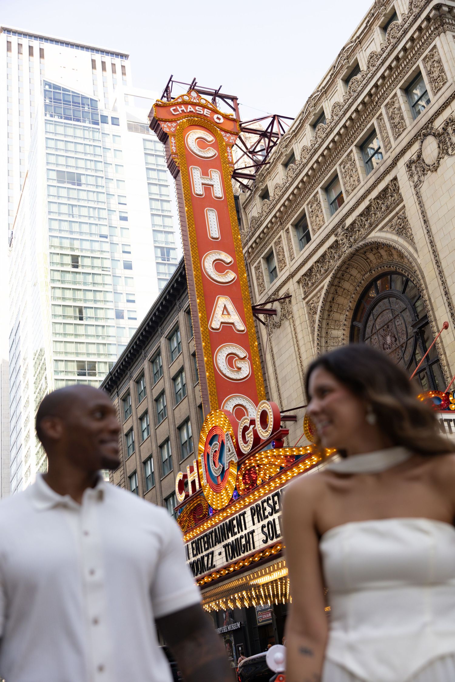 Couple sharing a romantic moment outside the iconic Chicago Theatre with its bright marquee lights.