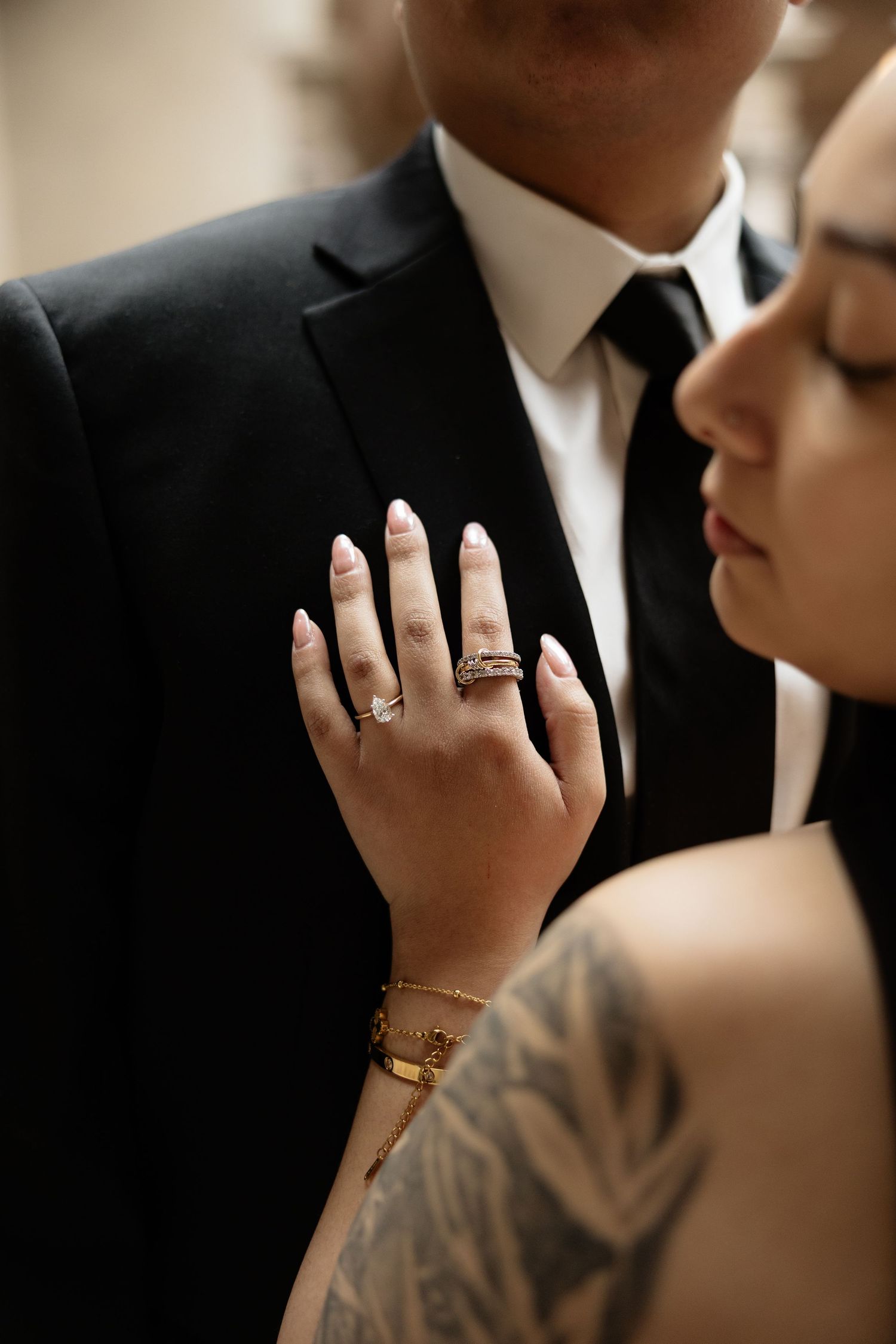 Close-up shot of hands with rings and tattoos in an intimate moment.