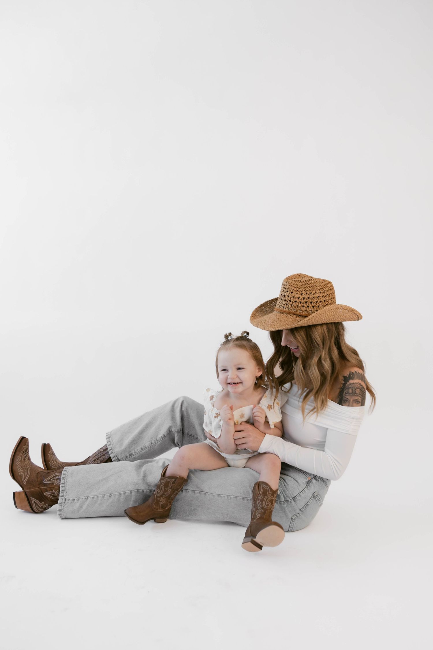 Relaxed lifestyle portraits with cowboy boots and hat against minimalist white backdrop.