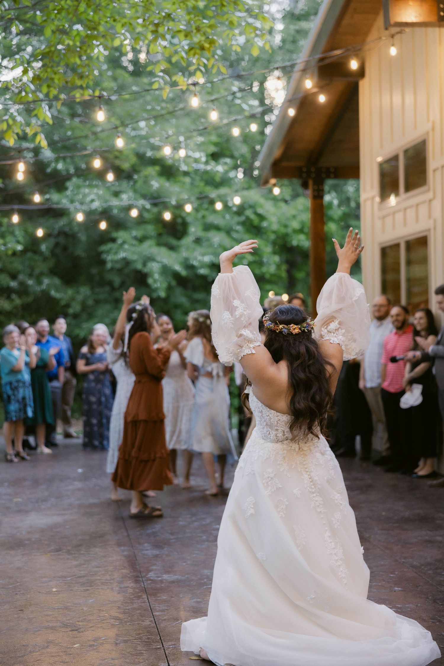 Dancing and celebrations on brick patio under string lights at outdoor wedding reception.