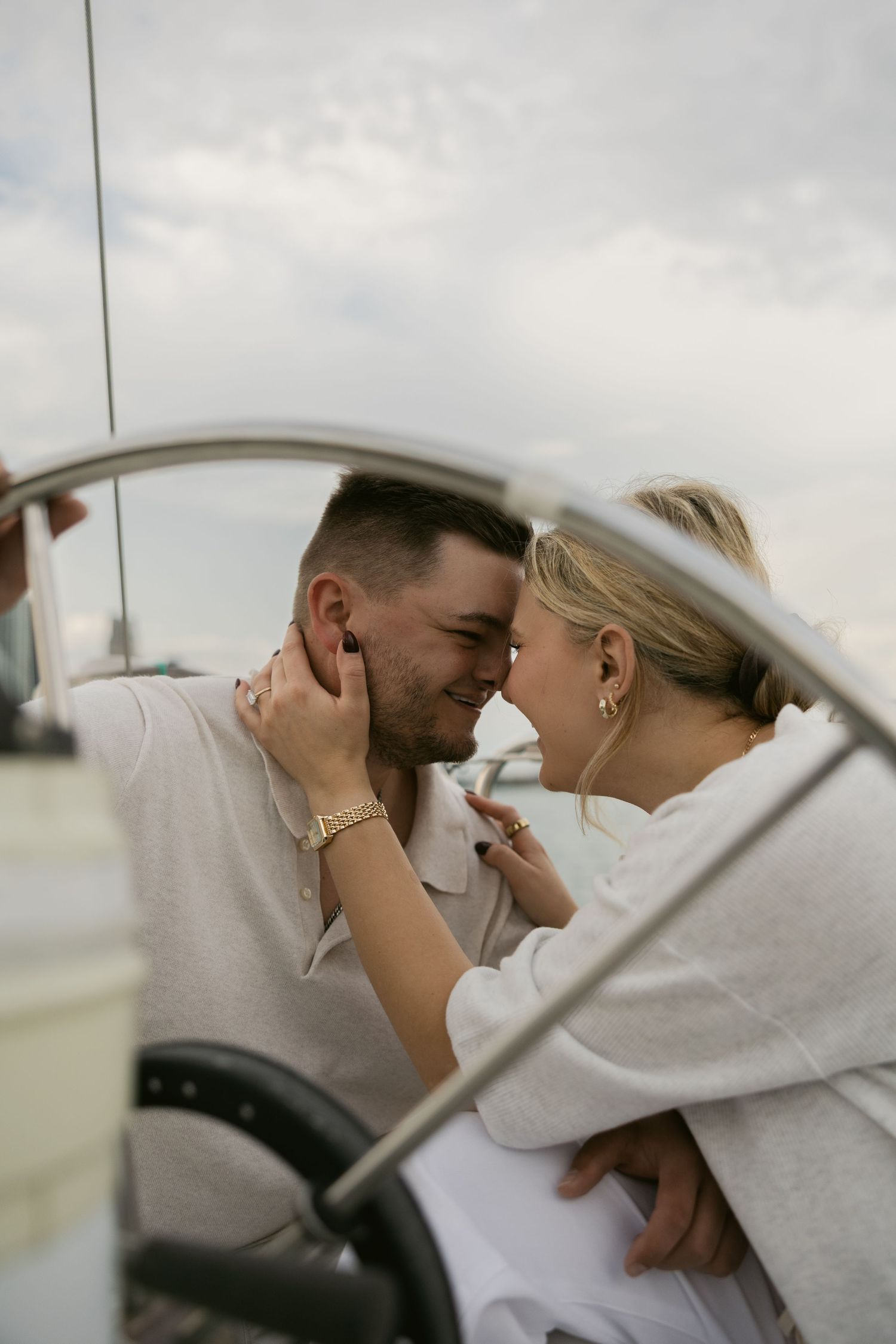 Romantic couple sharing tender moments on a boat deck during sunset.