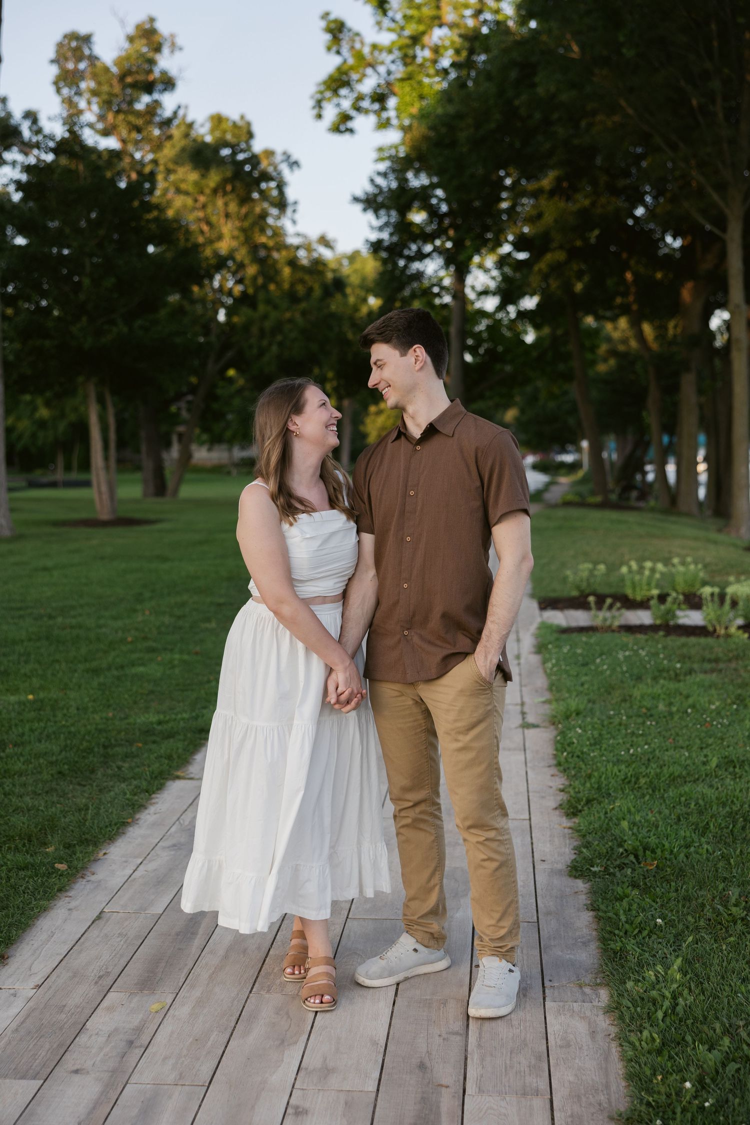 A couple shares romantic moments on a wooden boardwalk in a park during golden hour.