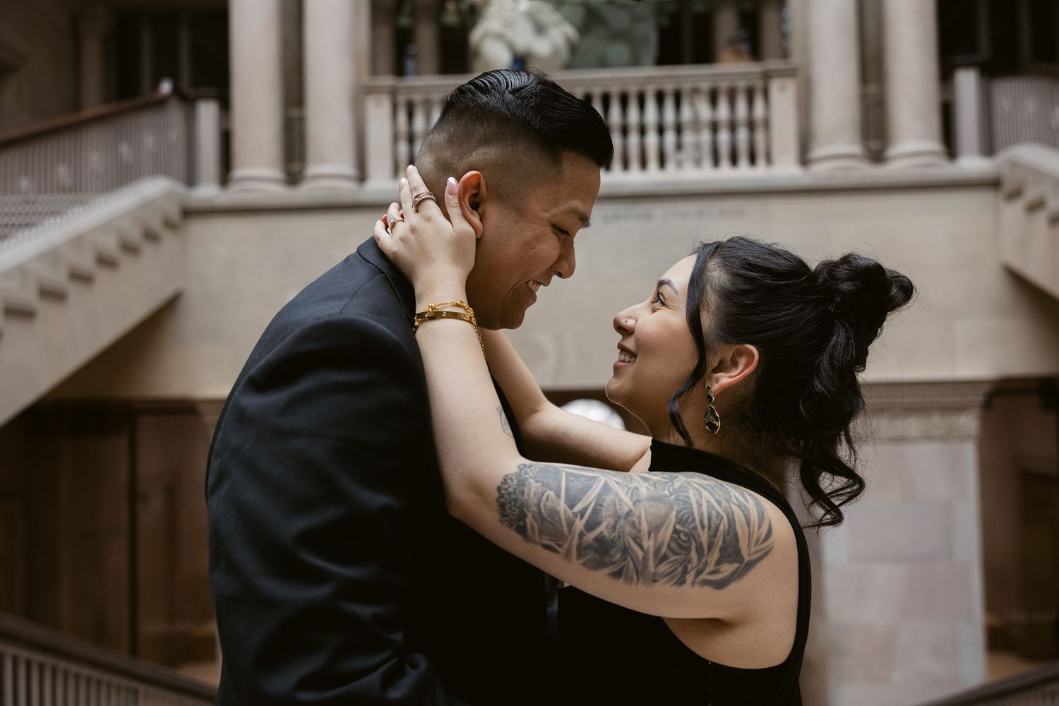 A romantic moment captured between two people in formal wear against stone architecture.