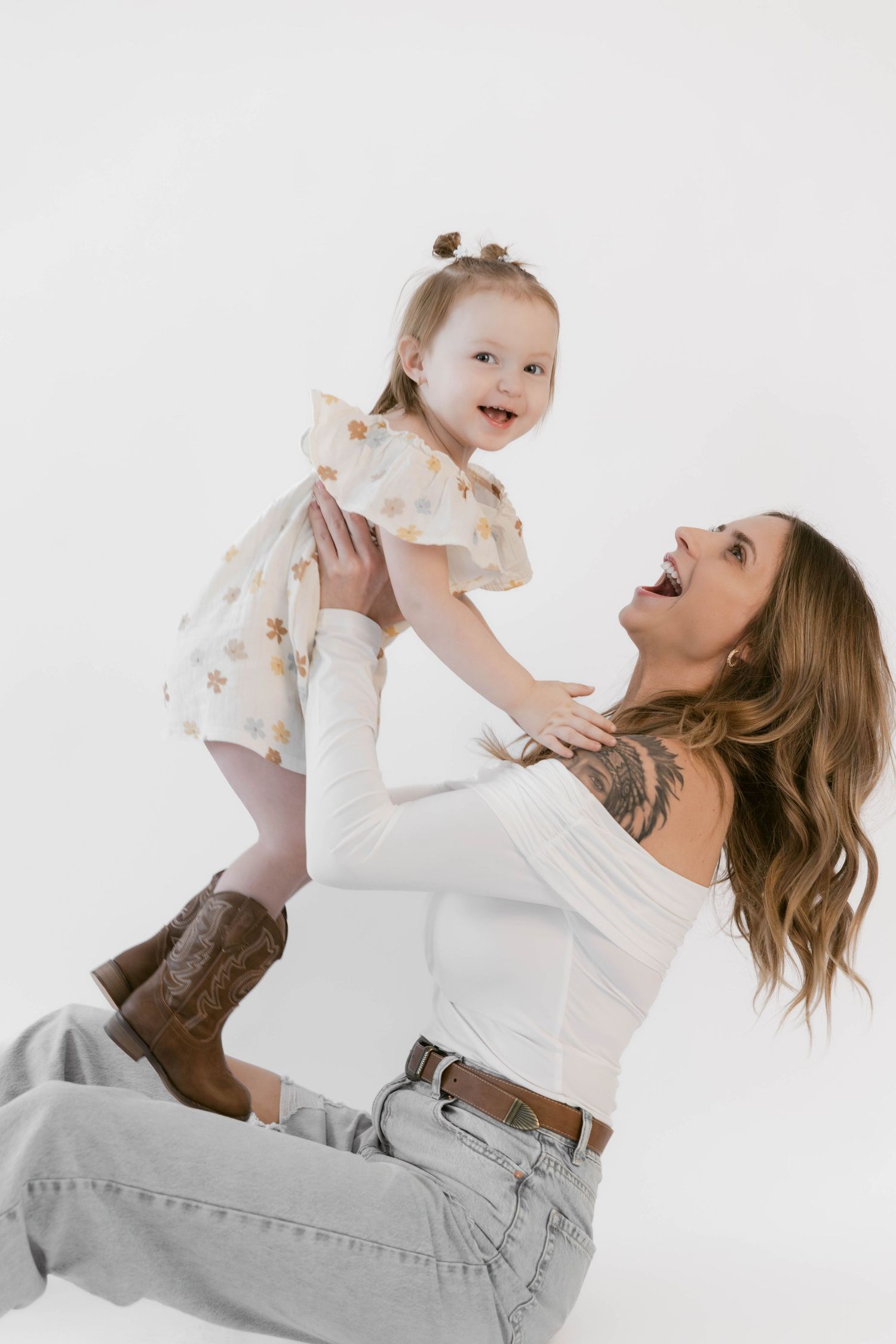 A playful lifting pose captured against white background during a studio photoshoot.