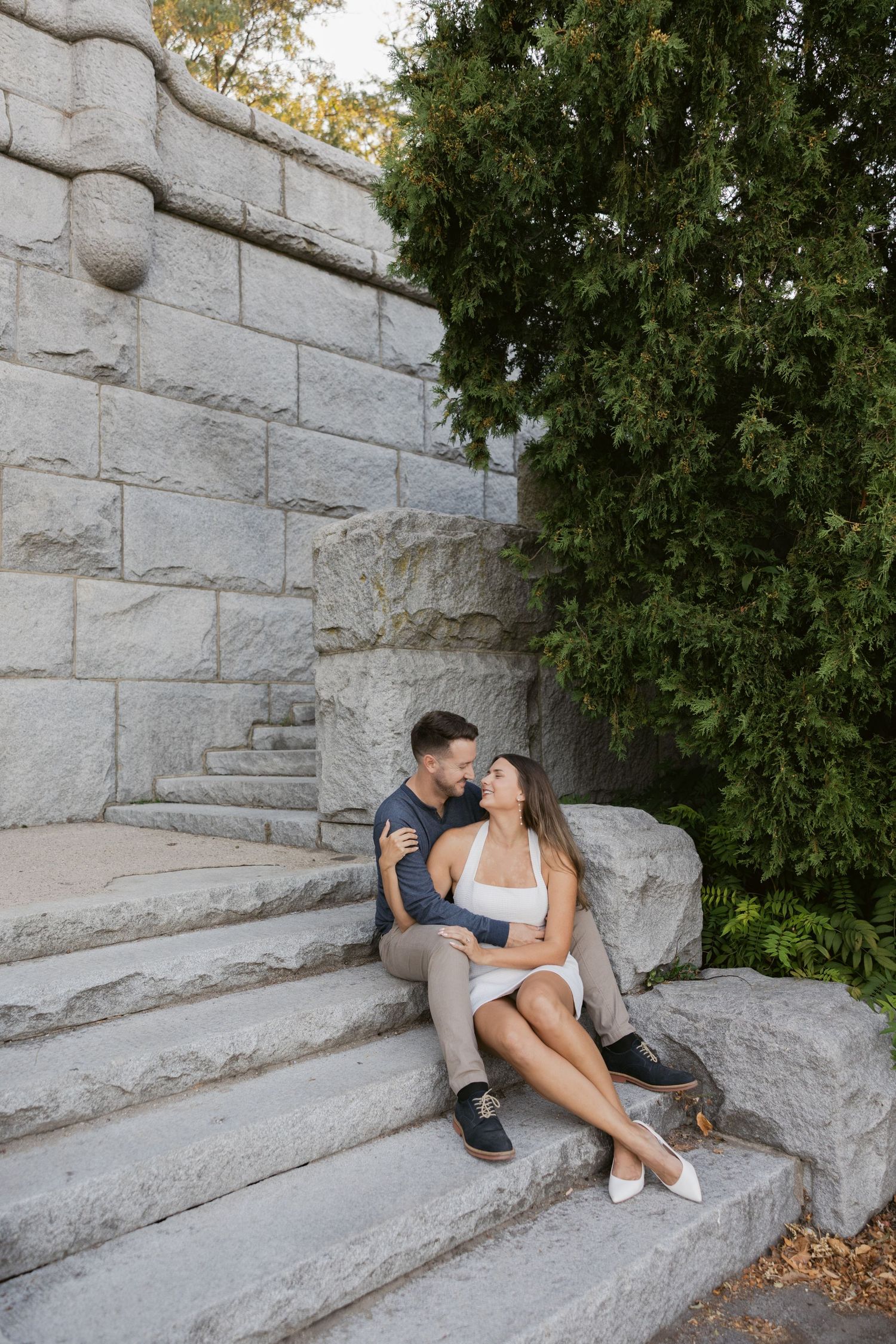 Couple relaxing on grey stone steps surrounded by greenery.
