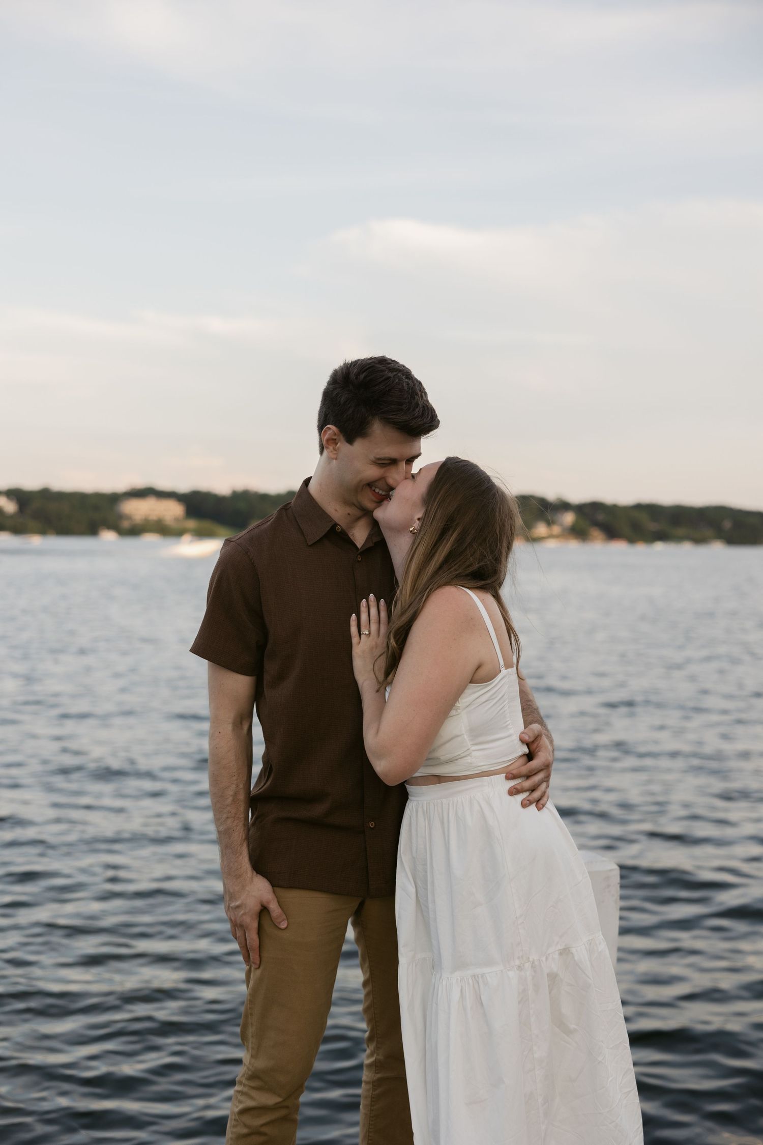 Intimate moment shared between couple on lakeside dock during golden hour.