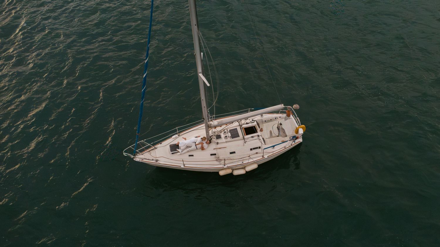 Panoramic view of sailboats anchored on calm ocean waters with cloudy horizon.