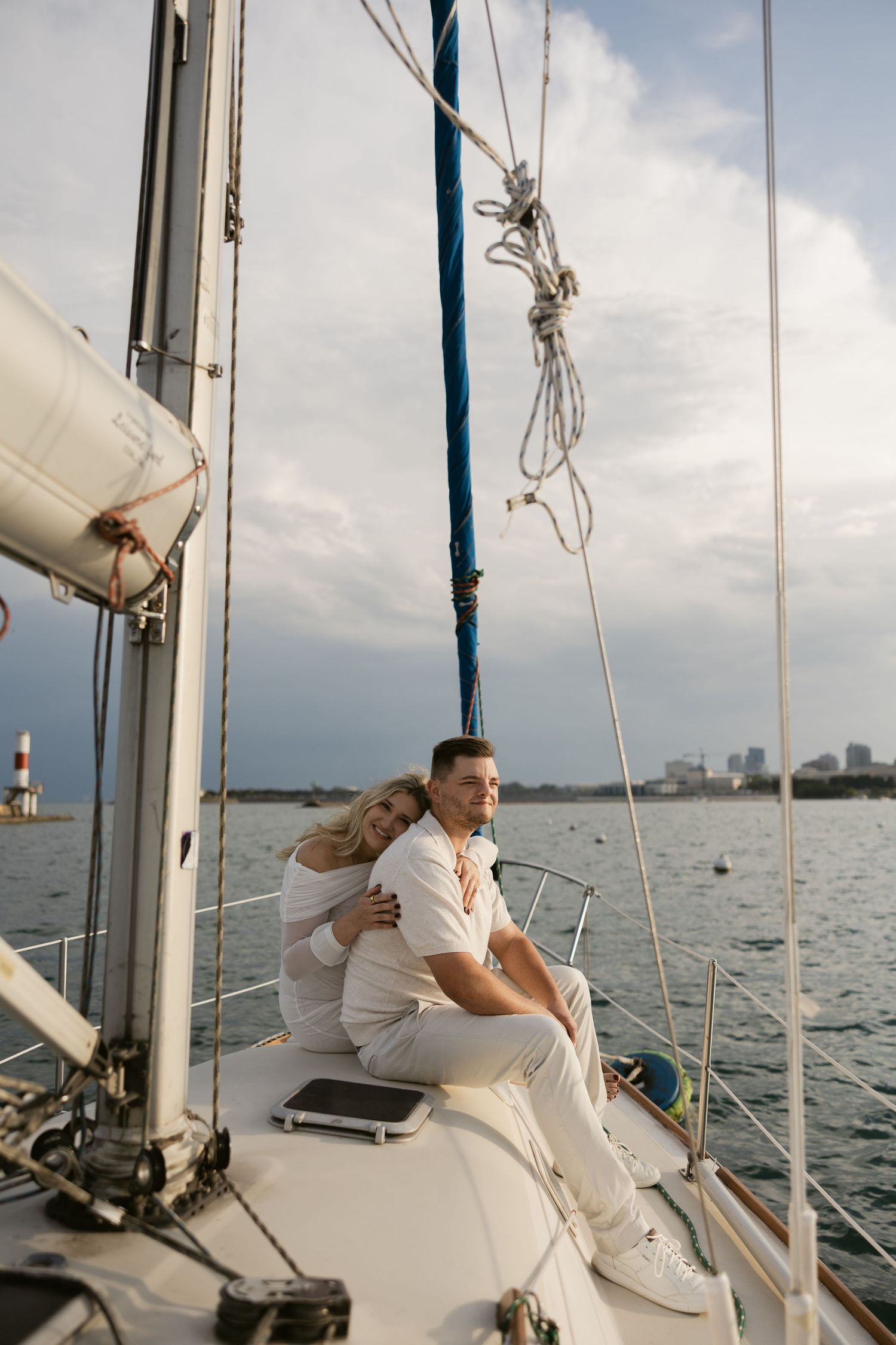 Couple enjoying romantic moments on deck of sailboat with water views.